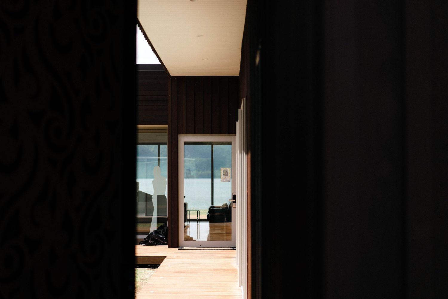 Minimalist hallway with glass walls leading to bright open space with ocean view.