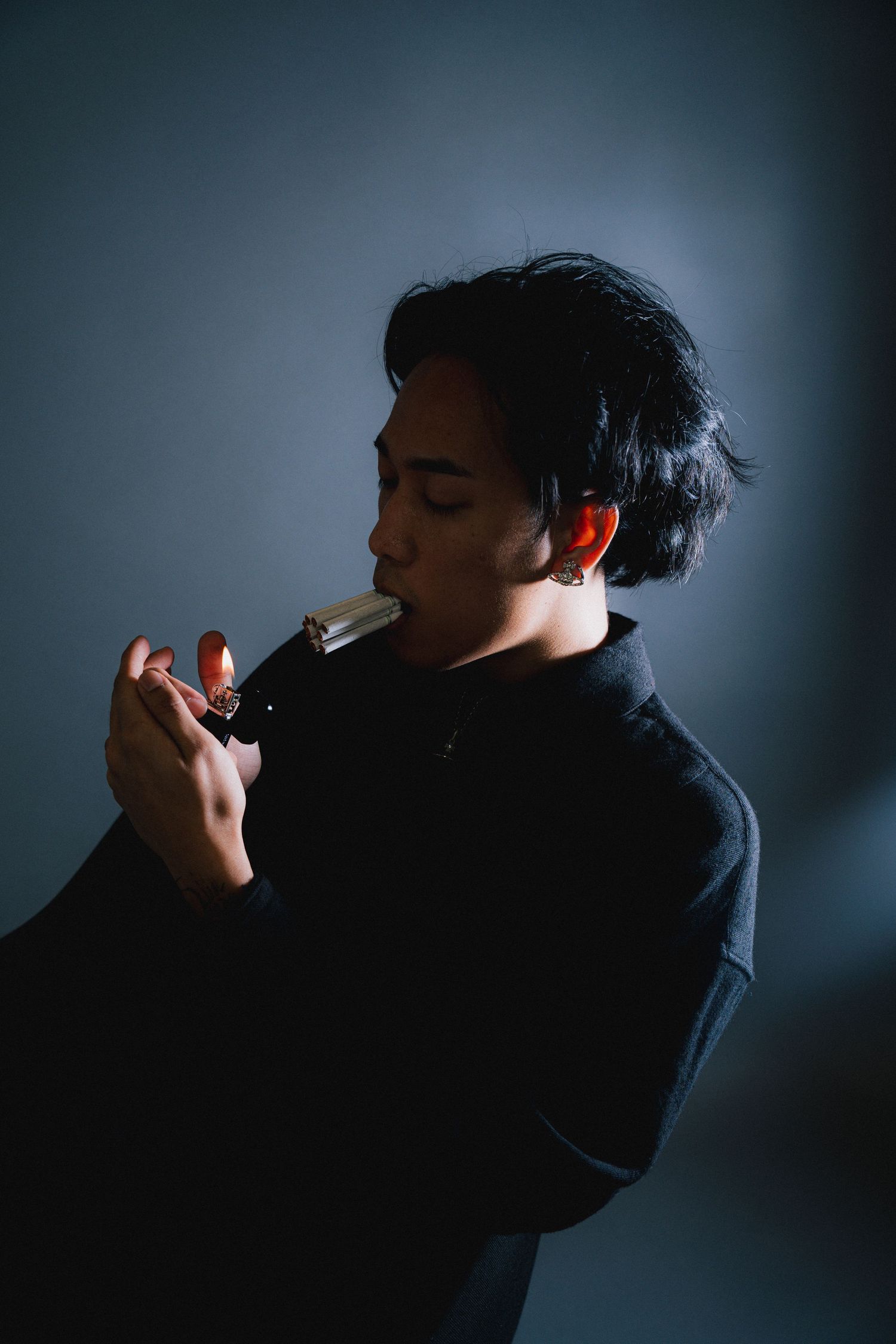 Dark silhouette series of someone smoking a cigarette against a blue-tinted backlit background.