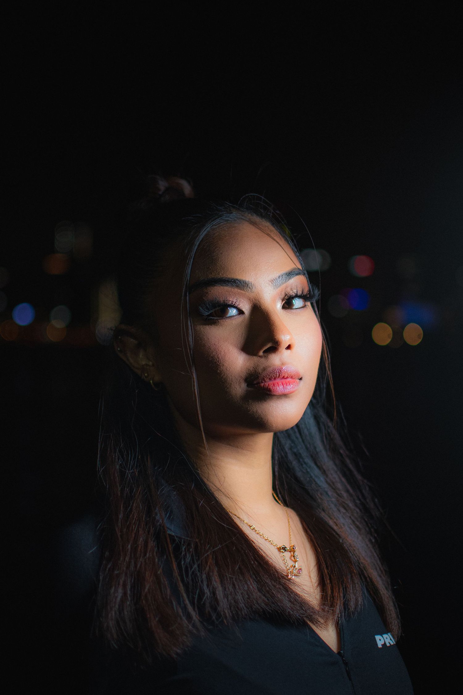Dramatic portrait with bokeh city lights in background and moody lighting.
