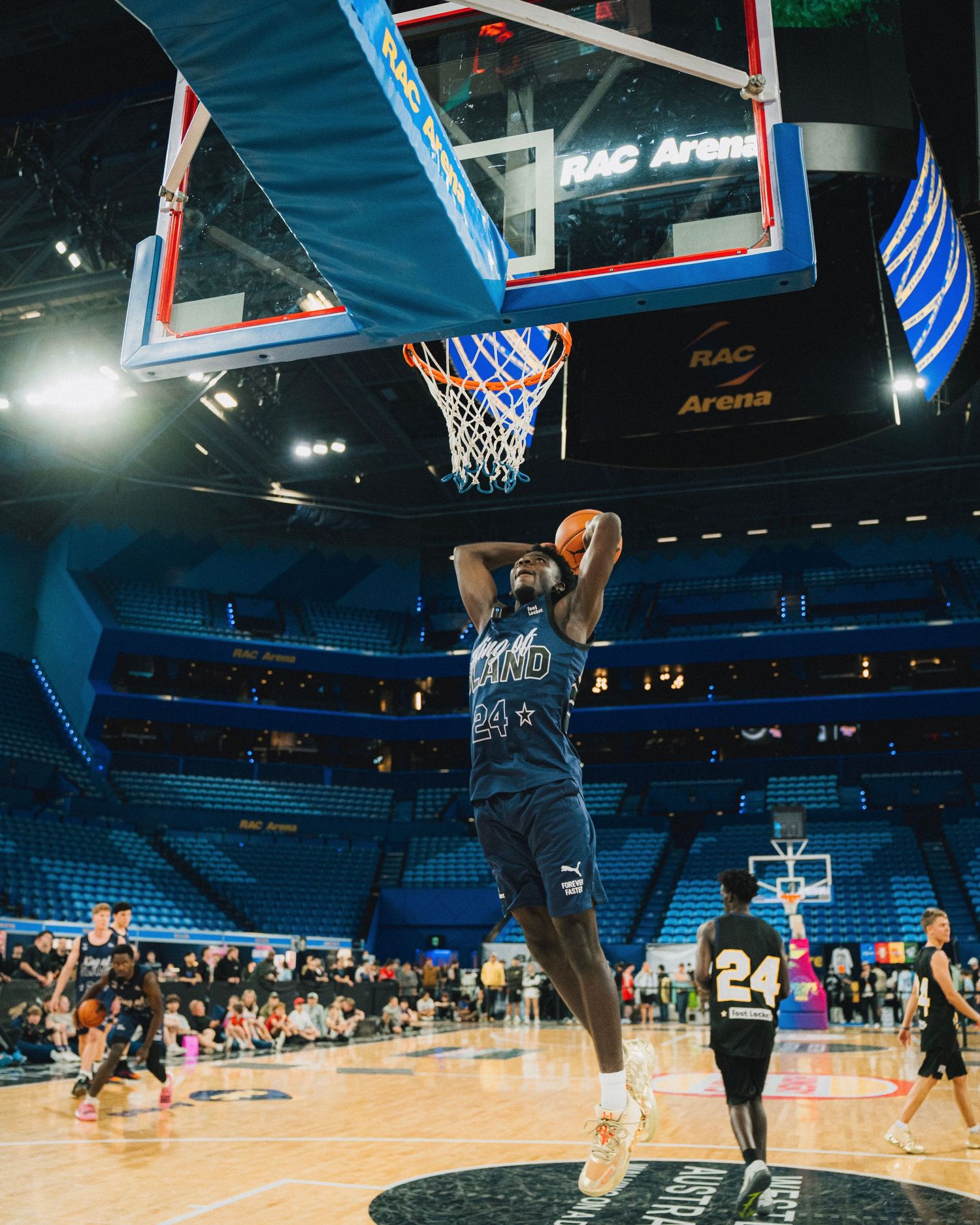Basketball player dunking at NBA arena with empty blue seats in background.