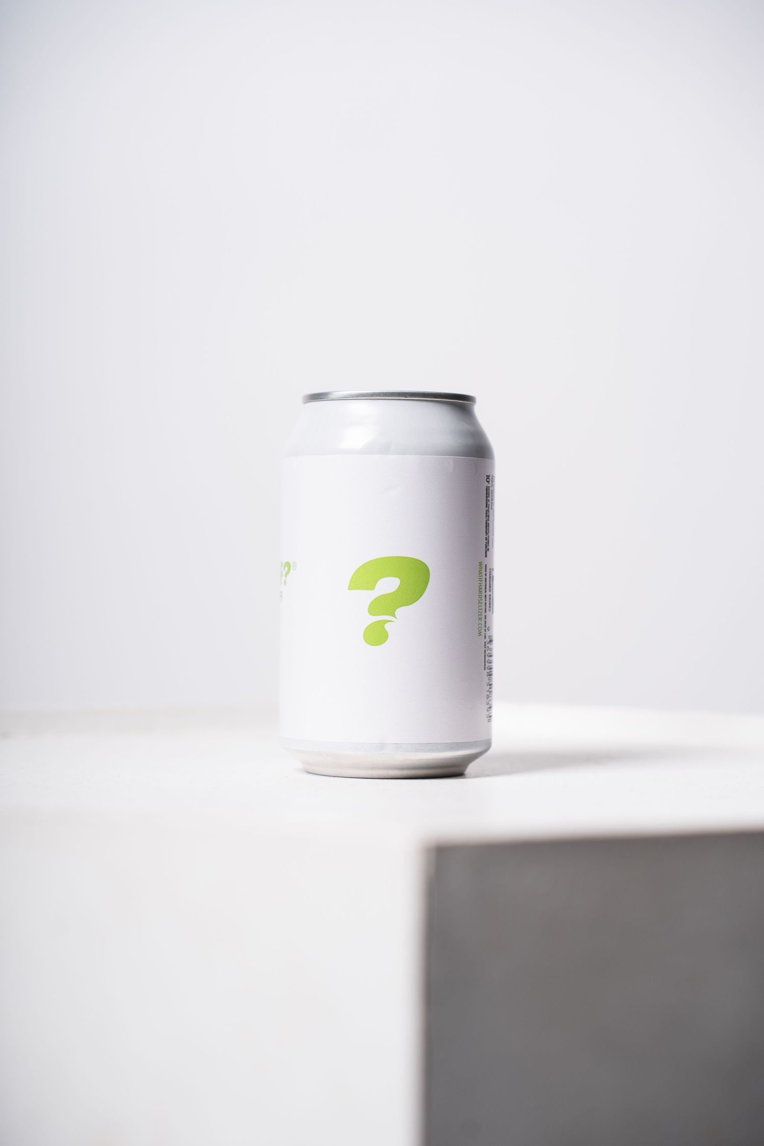 White aluminum beverage can with green question mark design against light background.