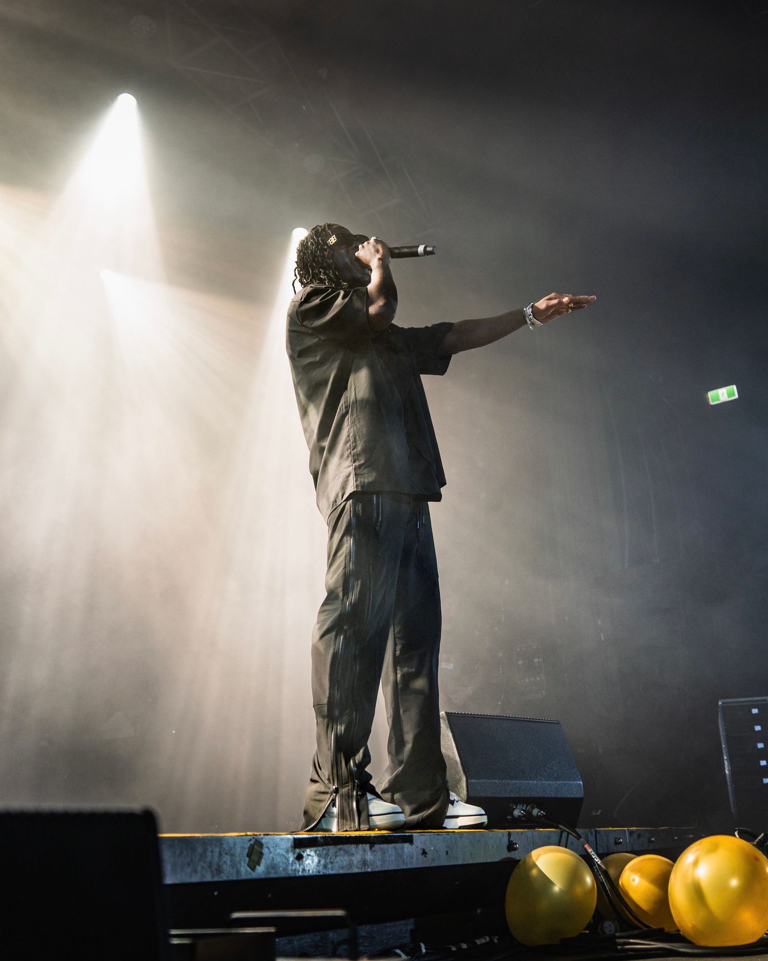 Silhouetted performer stands on stage with arms outstretched in dramatic lighting.