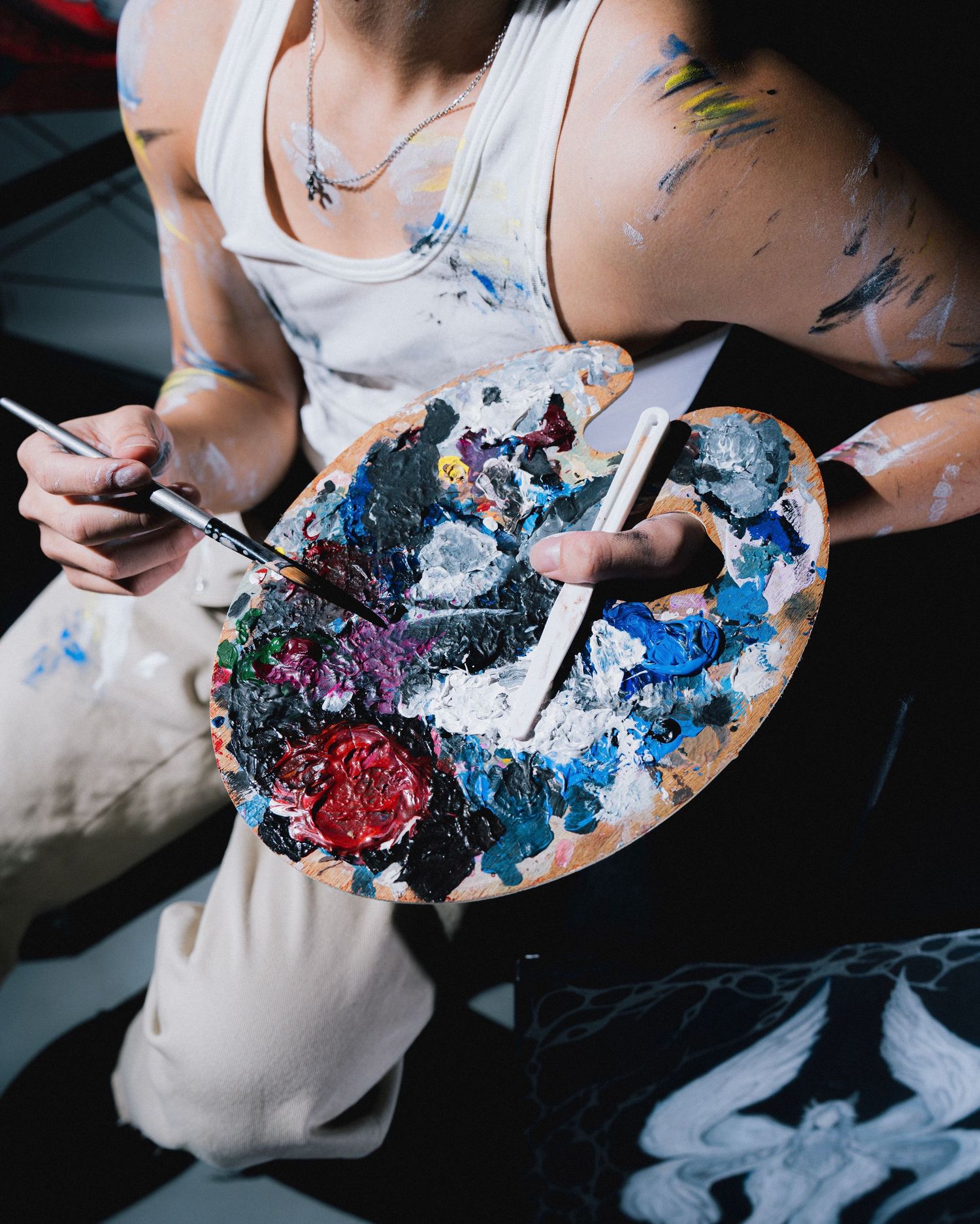 Close-up of artist's hands holding paint palette with vibrant colors and brushes.