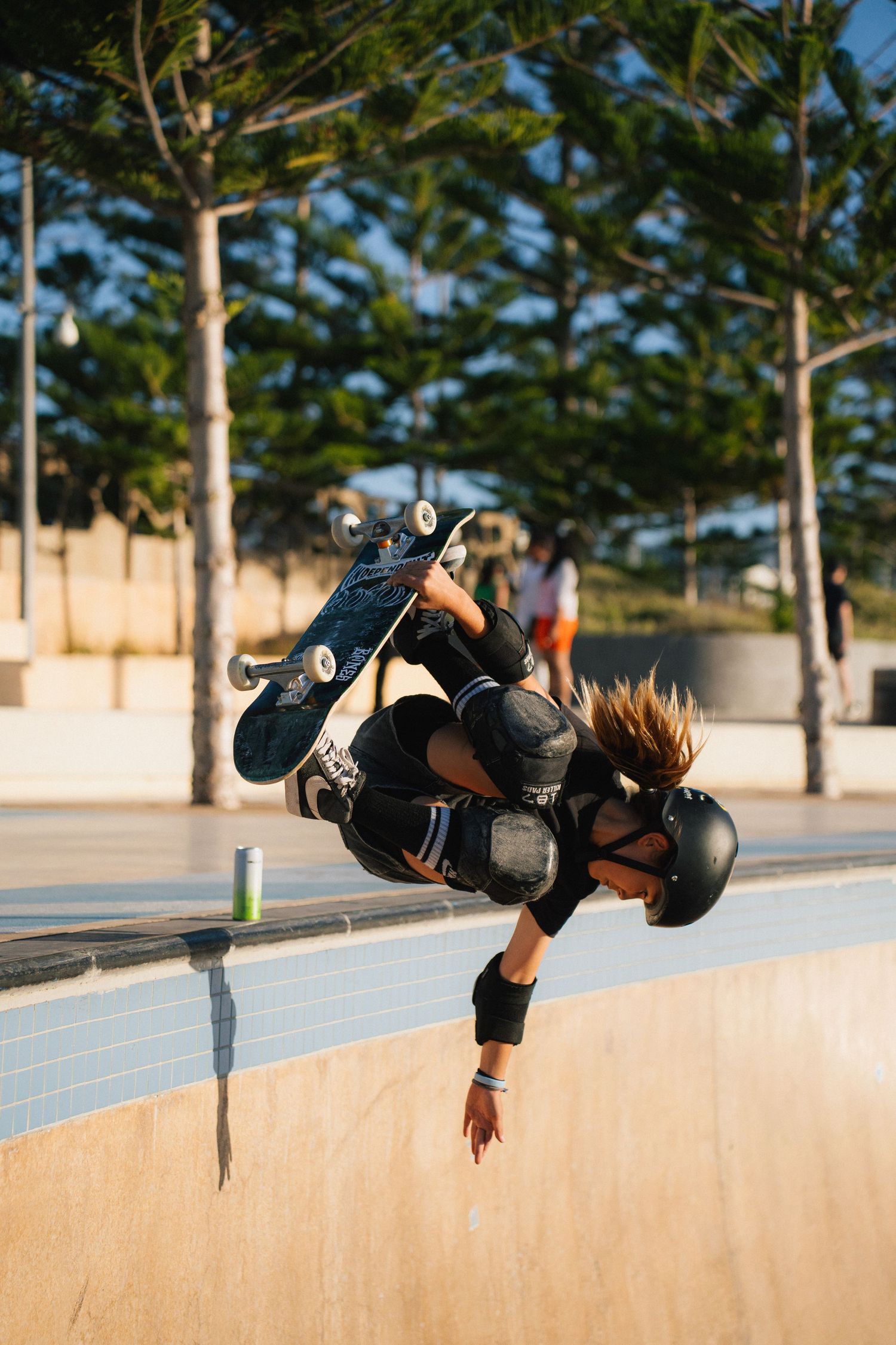 Skateboarder performing an inverted aerial trick at a skate park during golden hour.