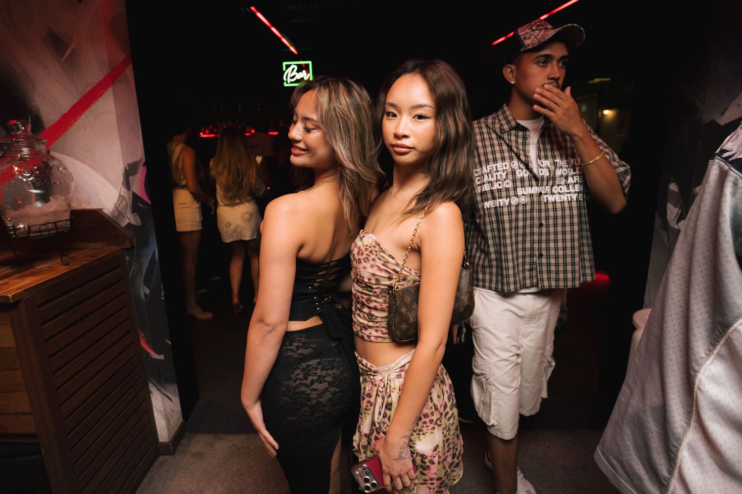 A group of people dancing and socializing at a nightclub with dim lighting and festive atmosphere.