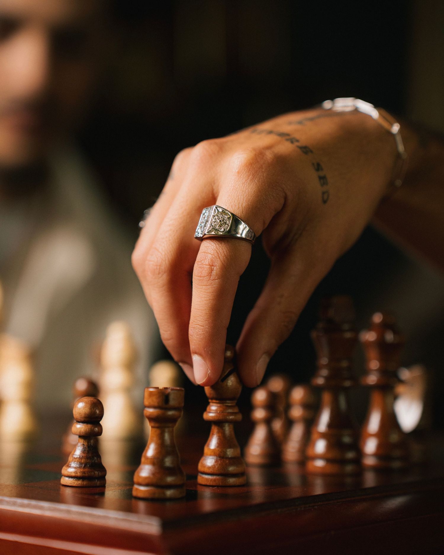 Close-up of a hand with ring making a move on wooden chess board.