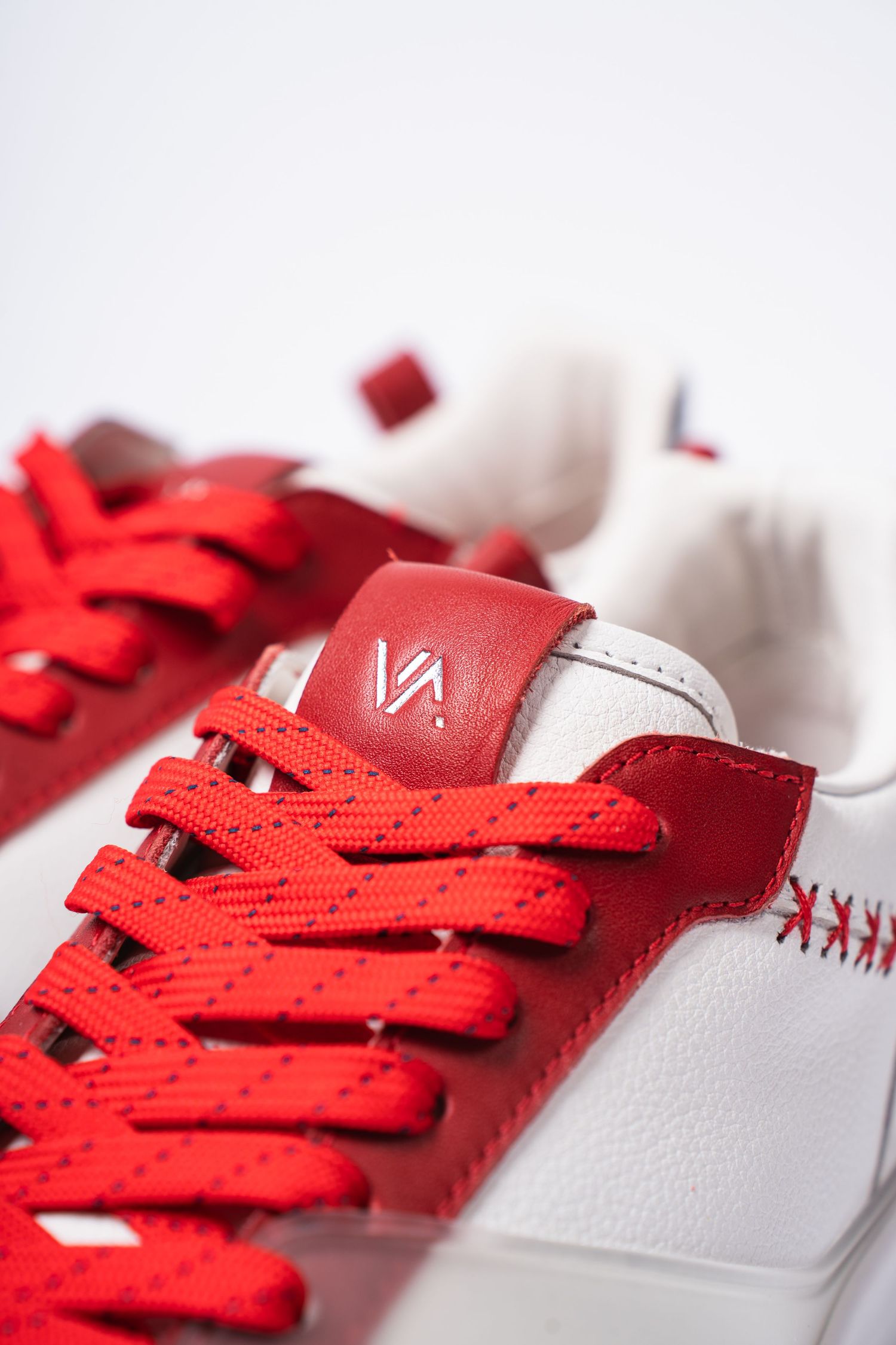 Close-up of red and white sneaker showing VA logo and bright red laces.