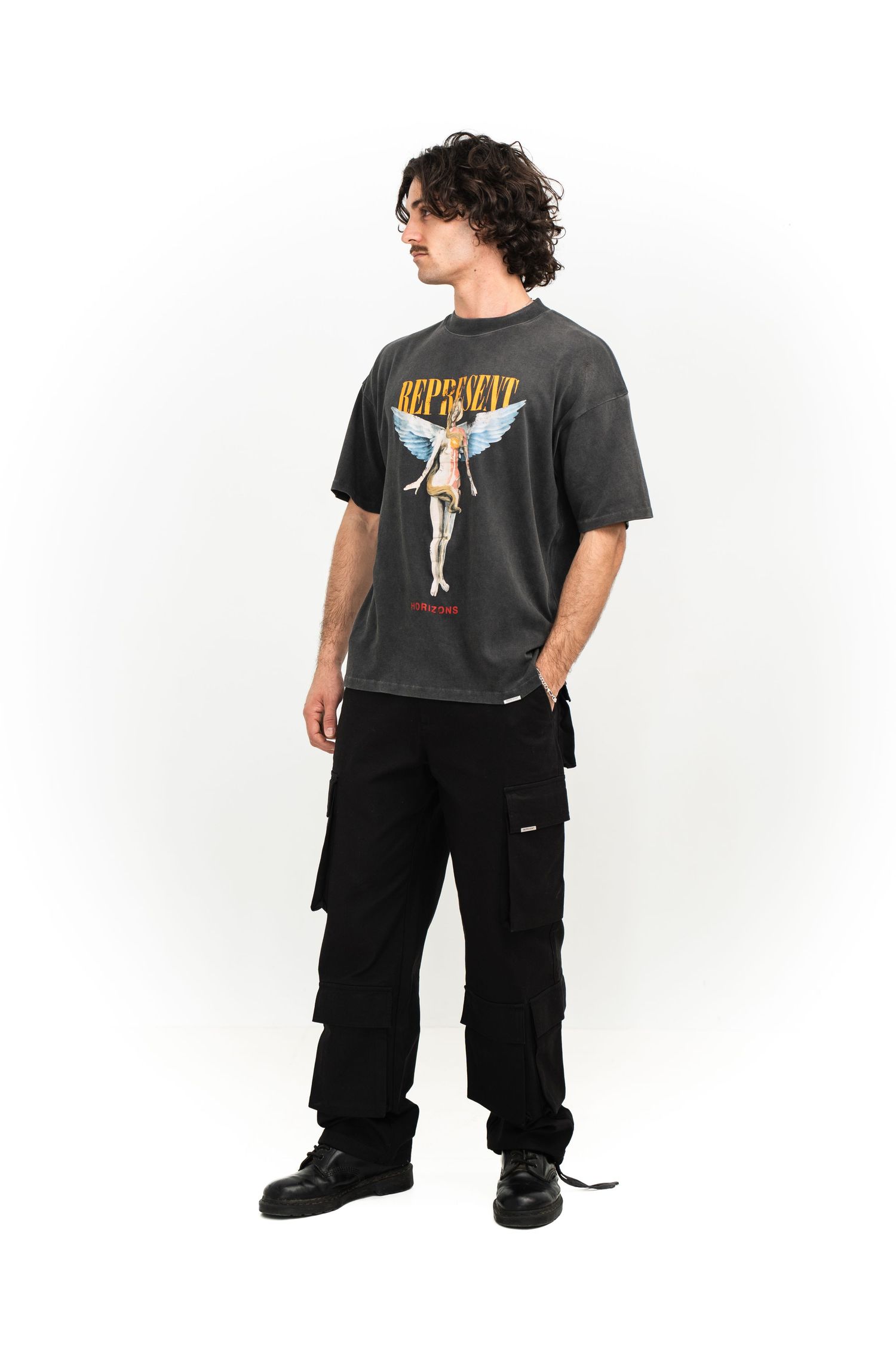 Model wearing vintage-style graphic t-shirt with black cargo pants and boots.