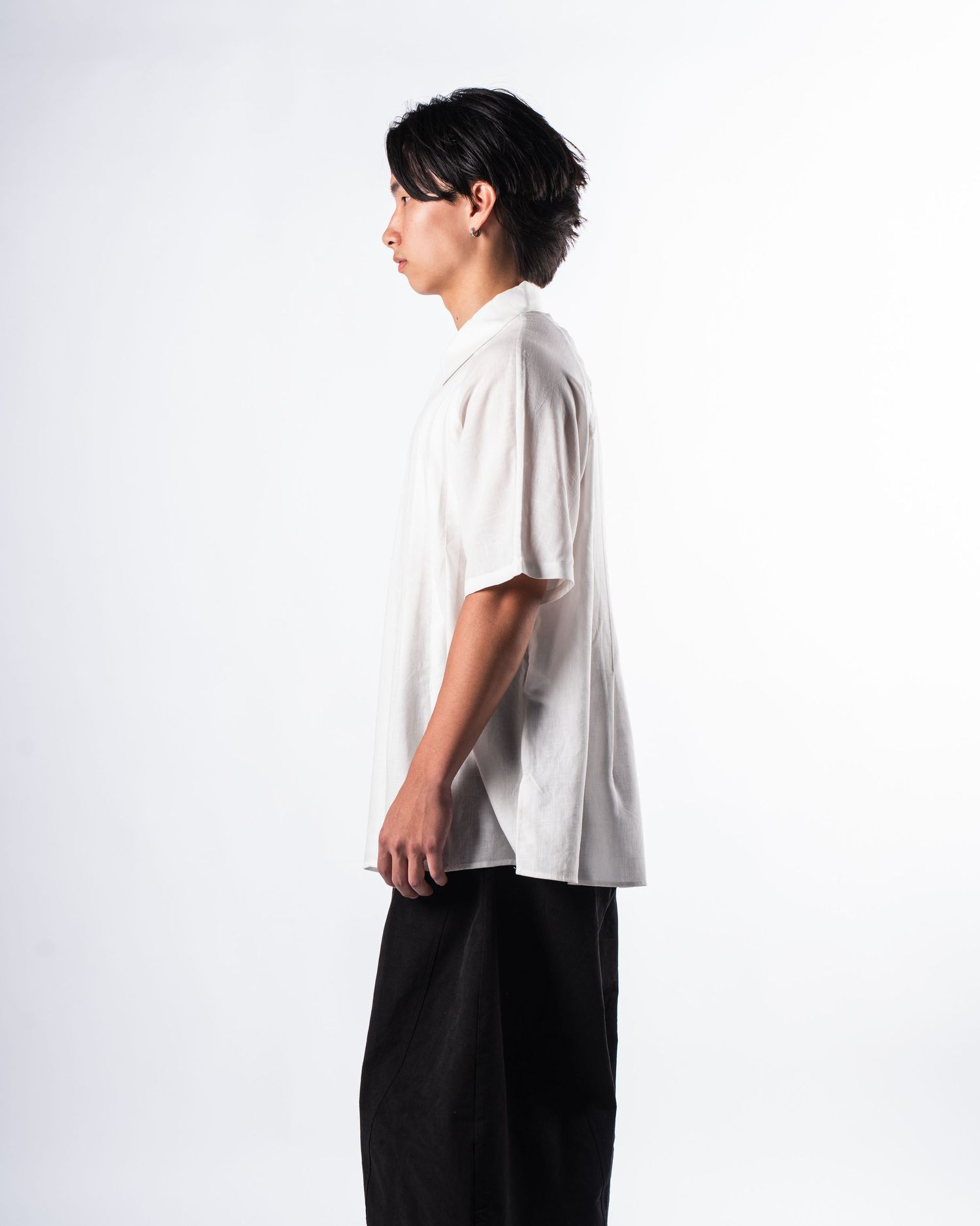 Minimalist fashion profile of a person wearing a white t-shirt and black pants against a white background.
