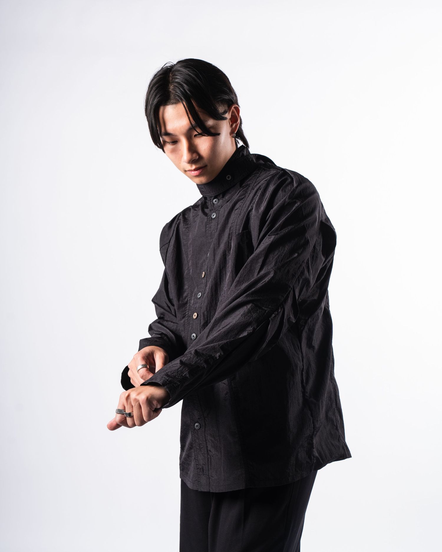 Person wearing a black jacket poses in moody artistic sequence against white background.