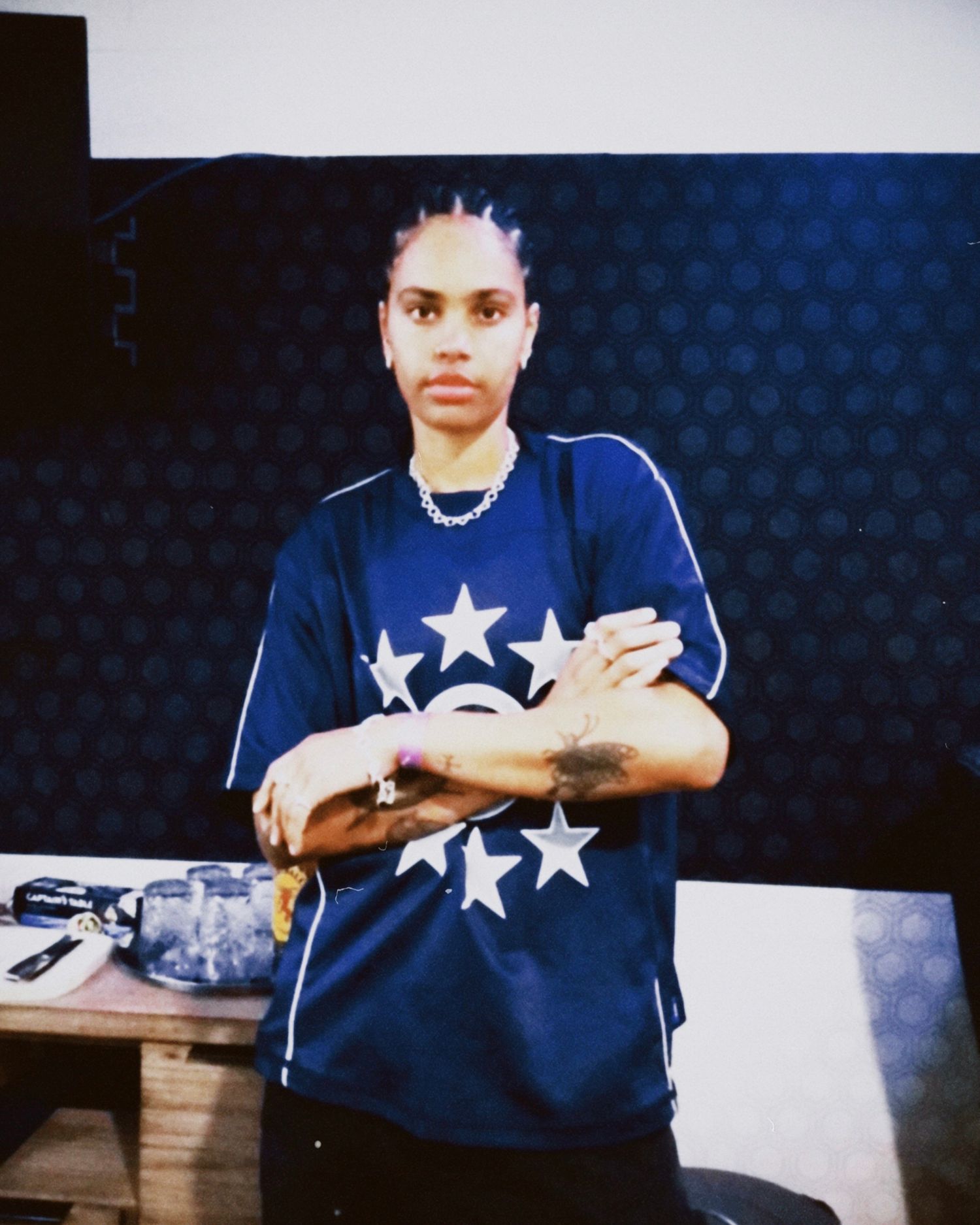 Person in blue jersey with white stars posing against textured blue background.