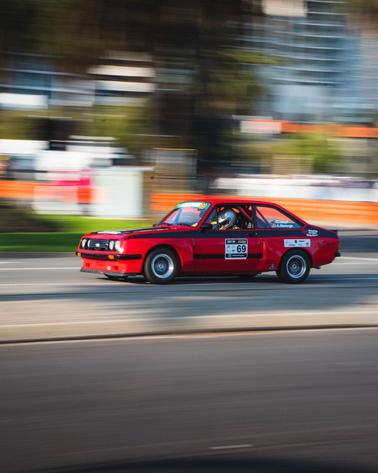 Red vintage BMW race car in motion on street track.