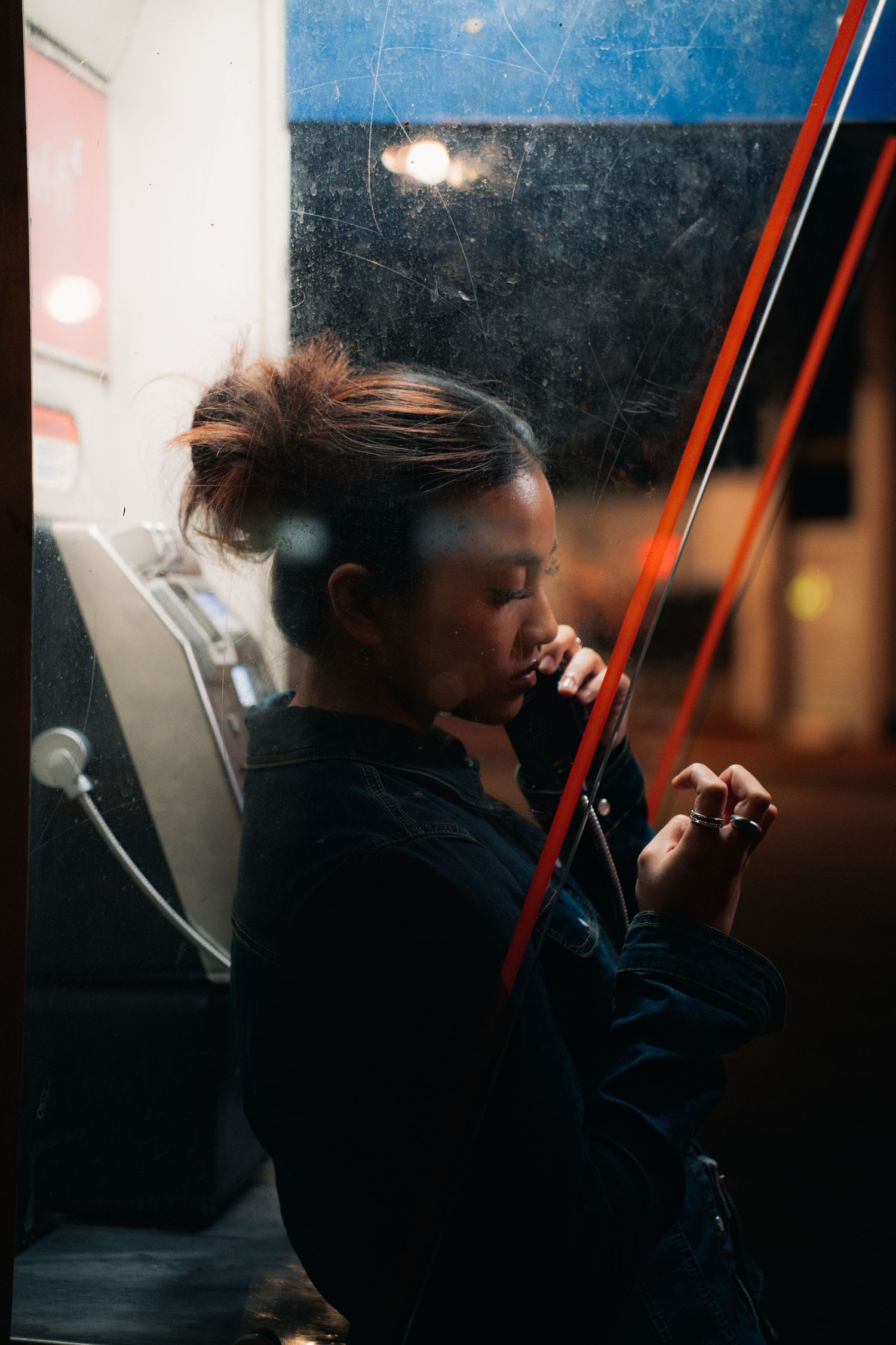 Silhouetted figure in darkness holds a violin bow while standing near illuminated windows.