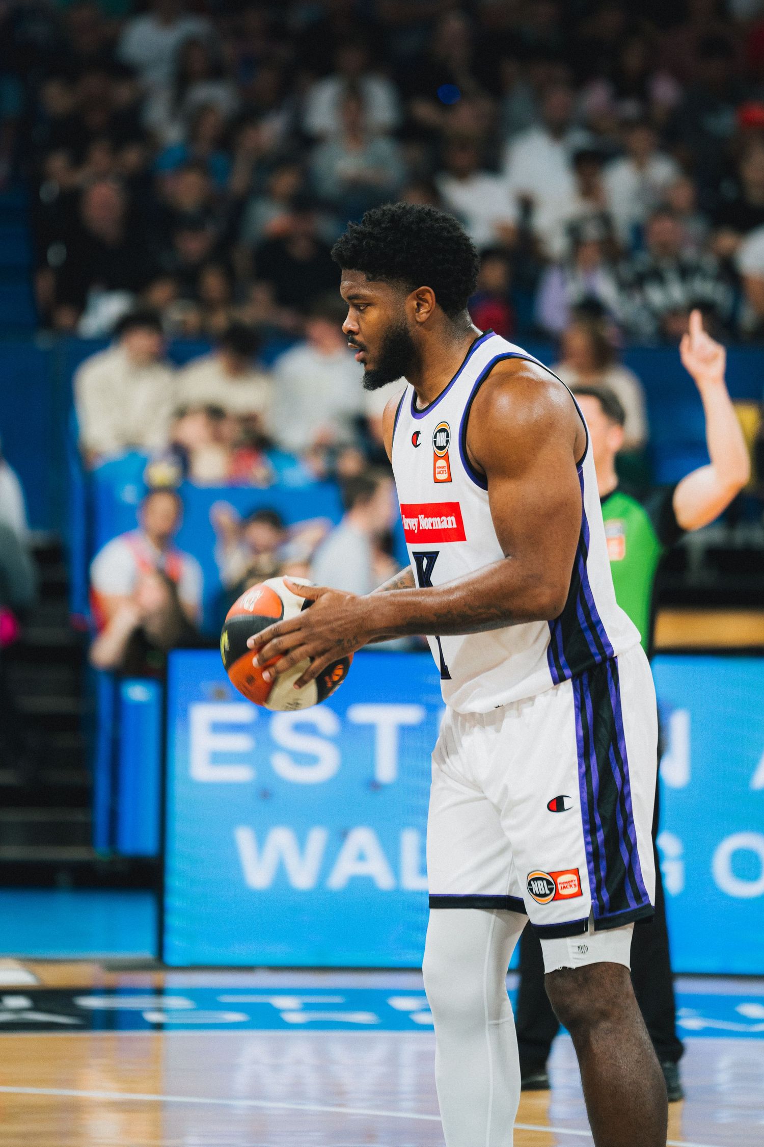 Basketball player in white uniform holding ball during competitive game.