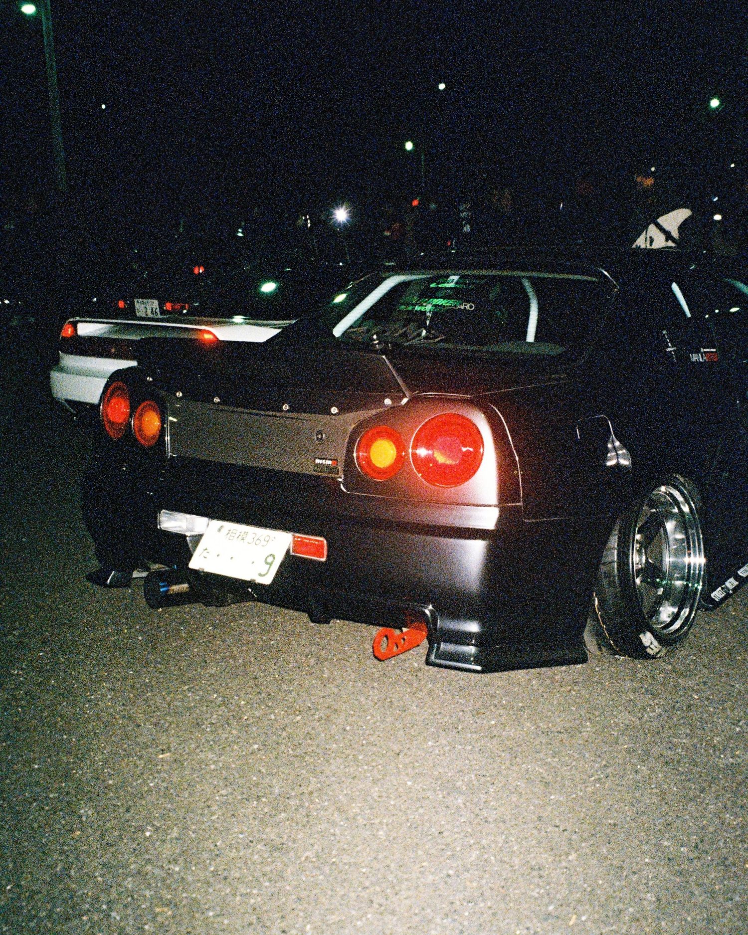 Modified Nissan Skyline with glowing taillights and custom wheels photographed at night.