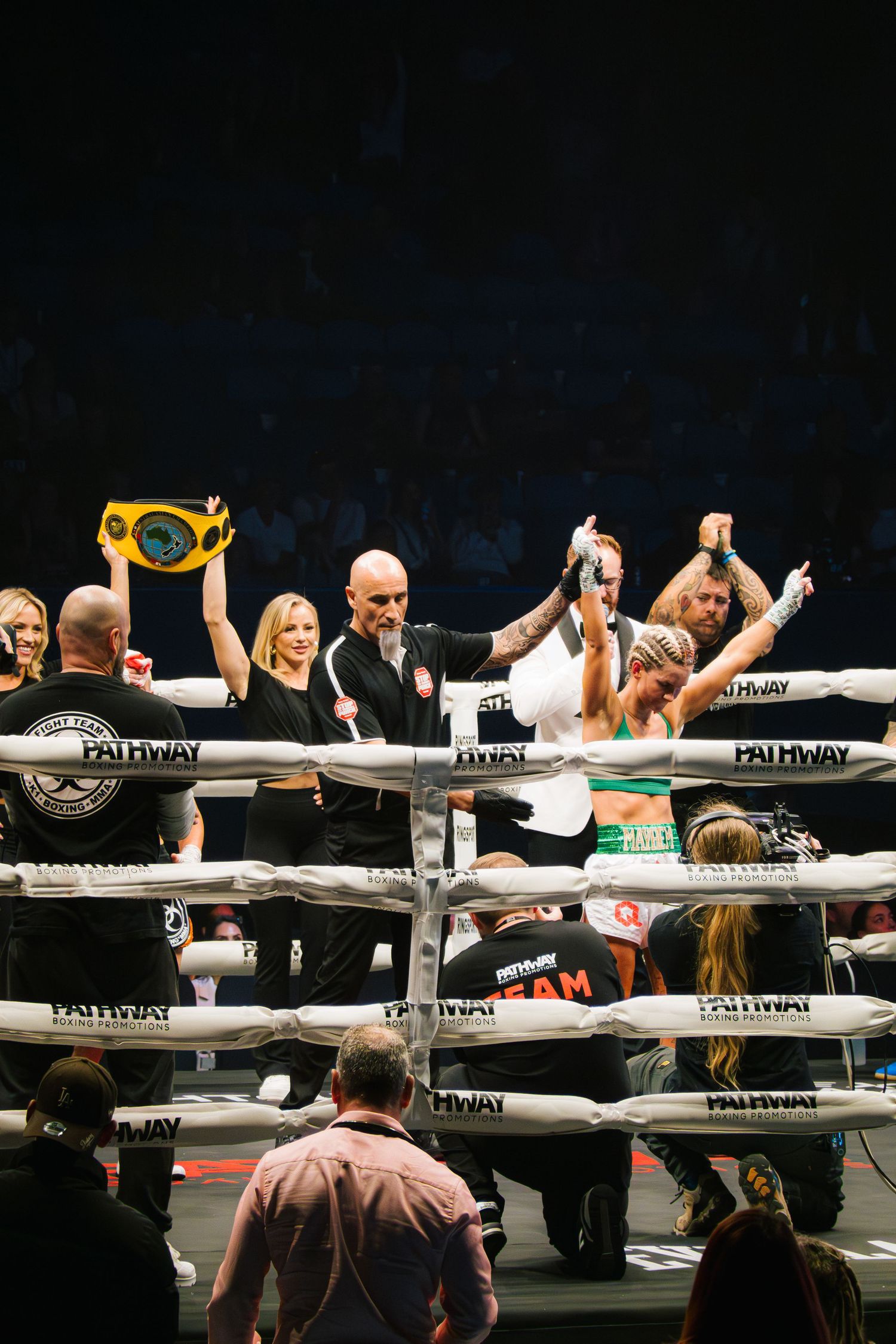 Victory celebration in boxing ring with champion being crowned after match.