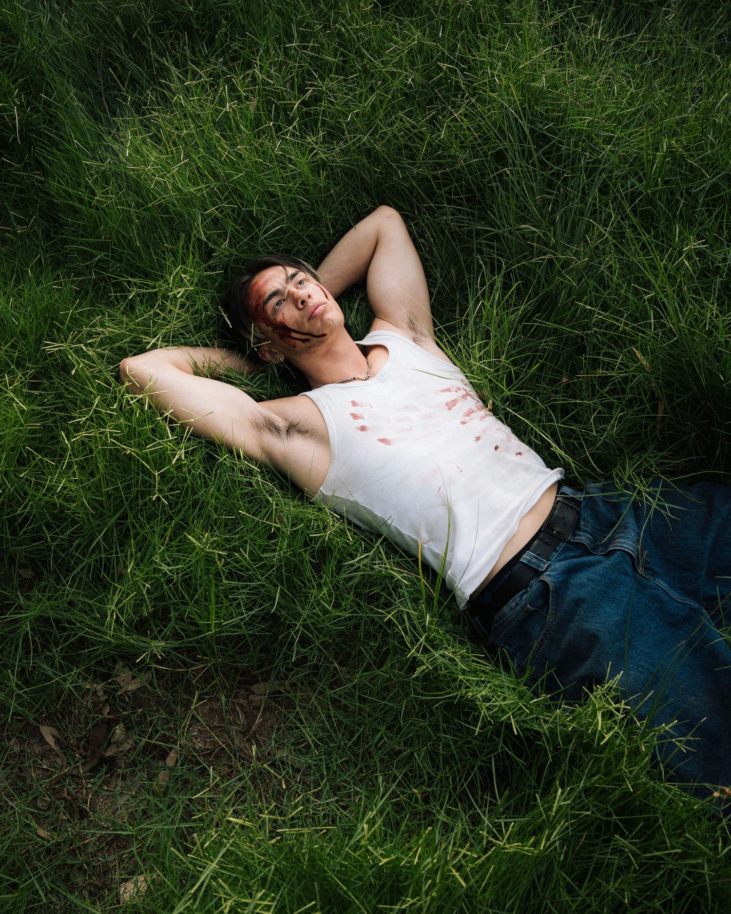 Person relaxing peacefully while lying in tall green grass on a sunny summer day.