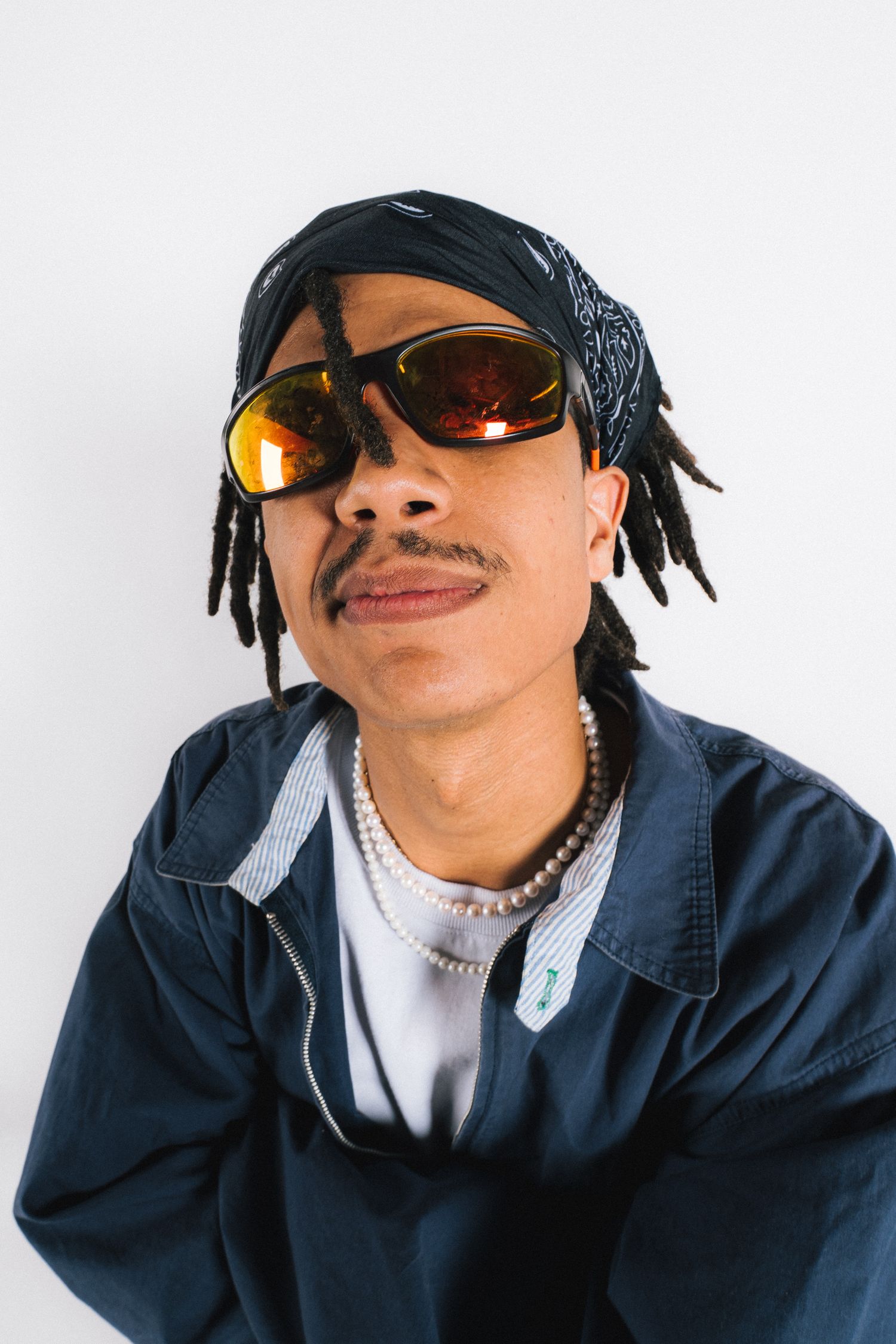 Person wearing sunglasses and navy jacket striking three different poses against white background.