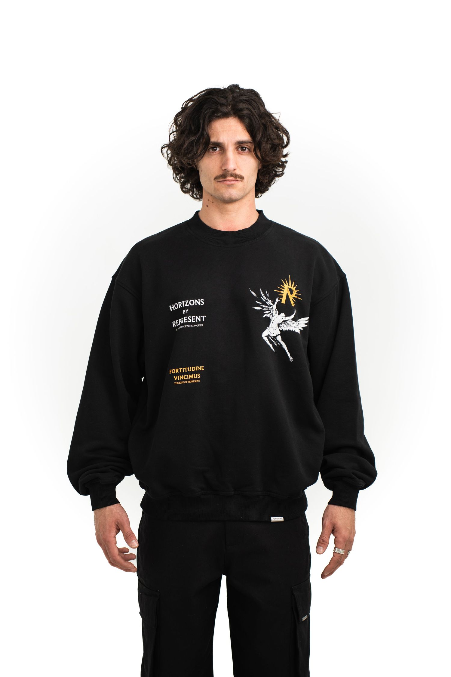 Model in black sweatshirt with graphic design and text wearing matching black pants.