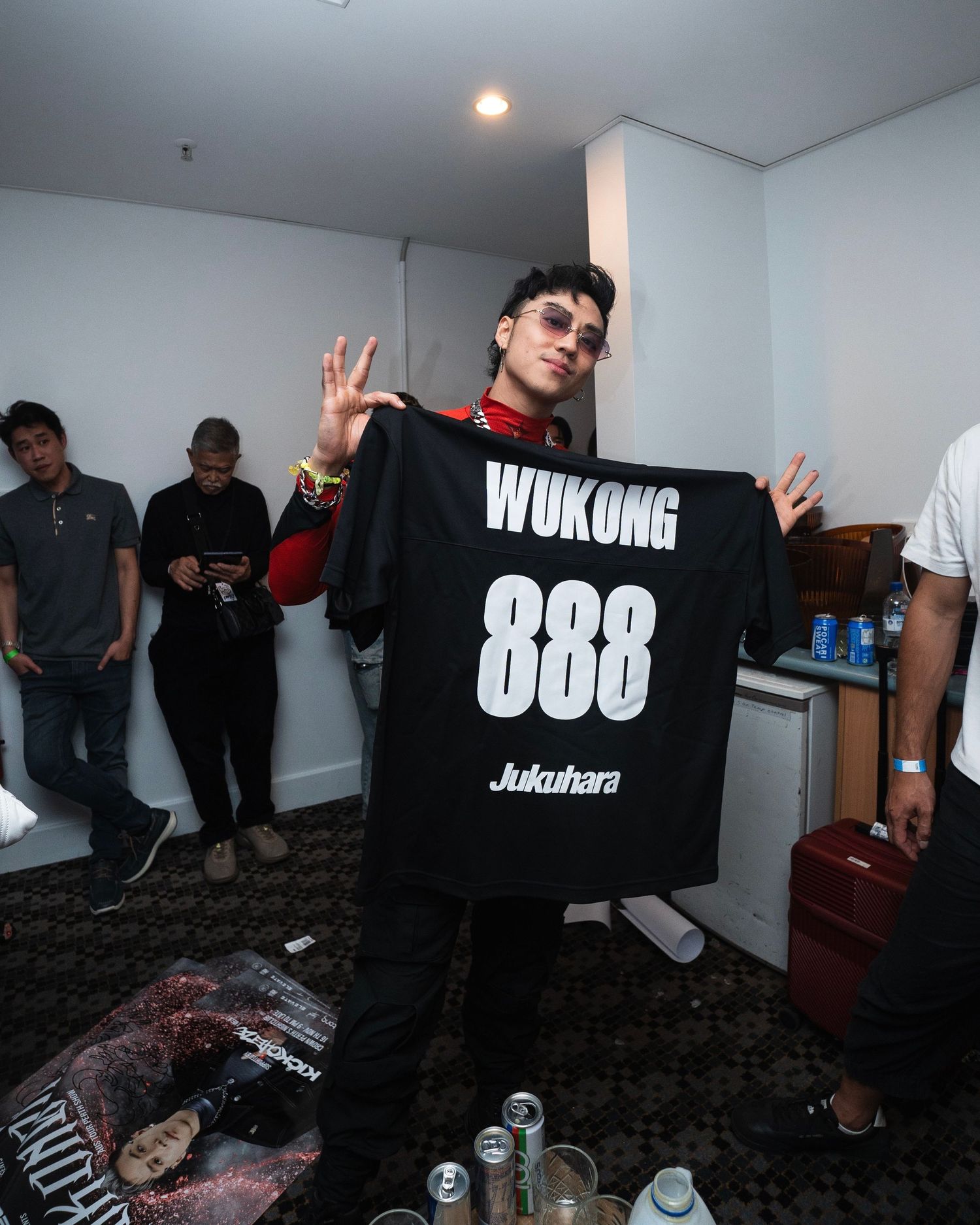 Person in sunglasses holds up a black t-shirt with 