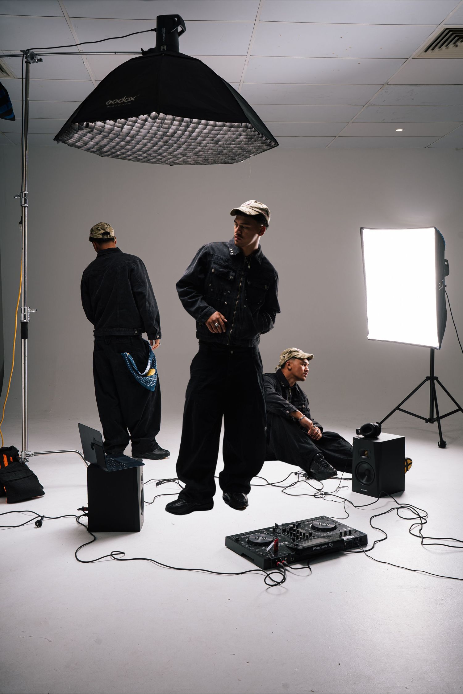 Behind-the-scenes photo from a professional photography studio with lighting equipment and people on a white backdrop.