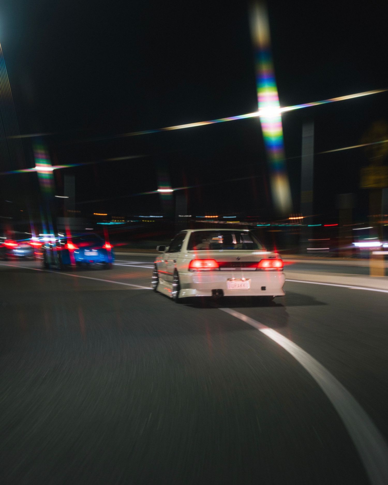 Modified sports sedan drifting on a curved road at night with motion blur.