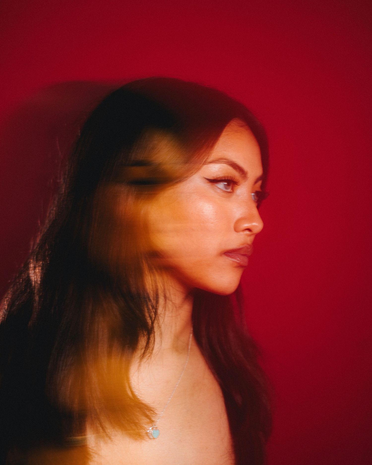 Artistic profile portrait with warm red lighting and motion blur effects.