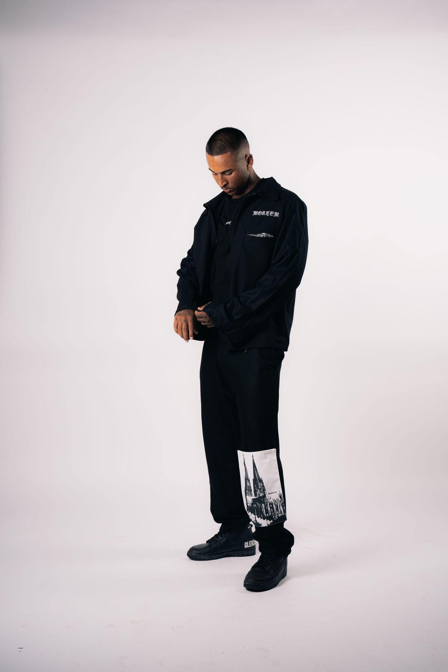 Person wearing all black streetwear outfit with graphic print details.