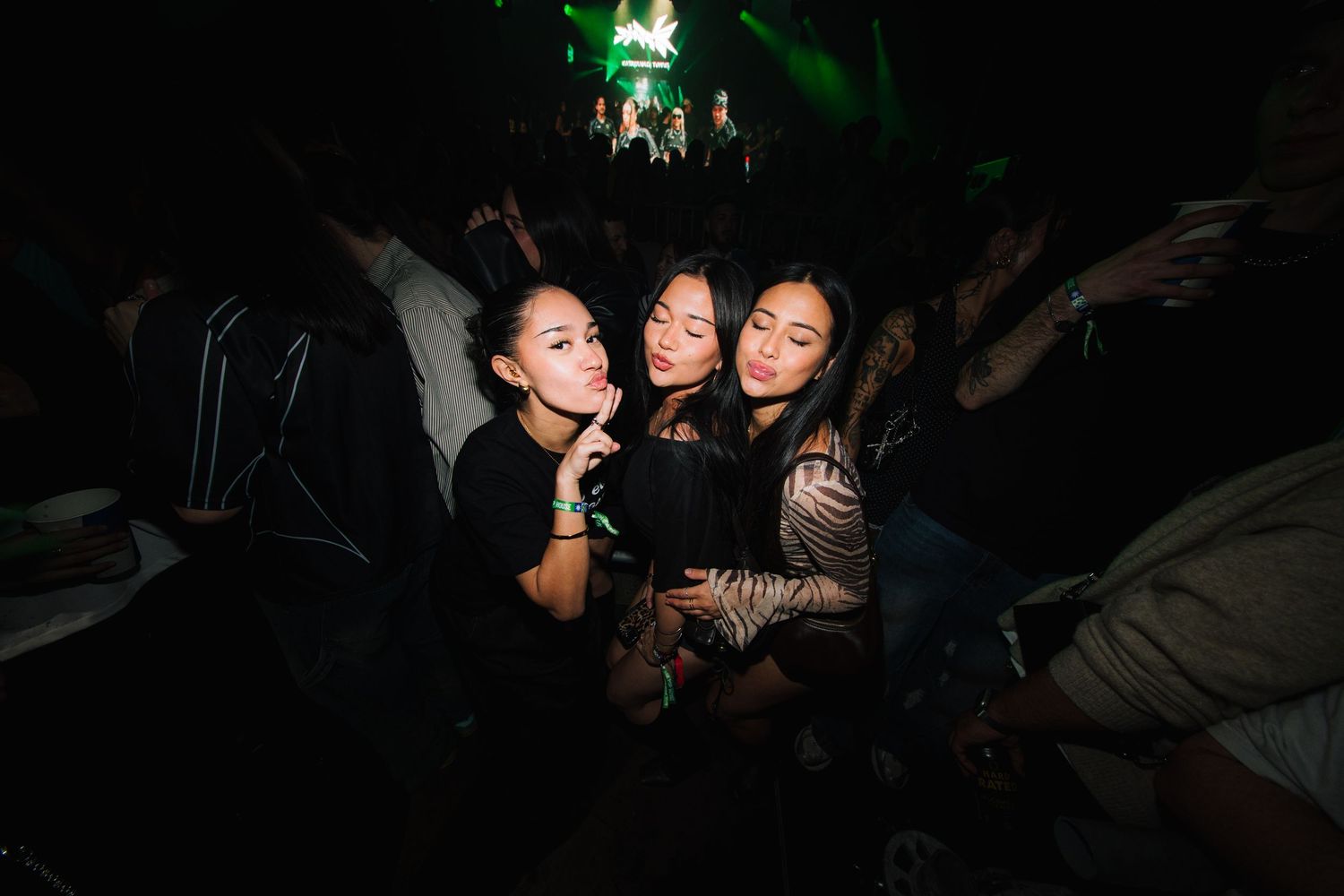 People enjoying themselves at a dimly lit nightclub or party venue with dynamic lighting effects.