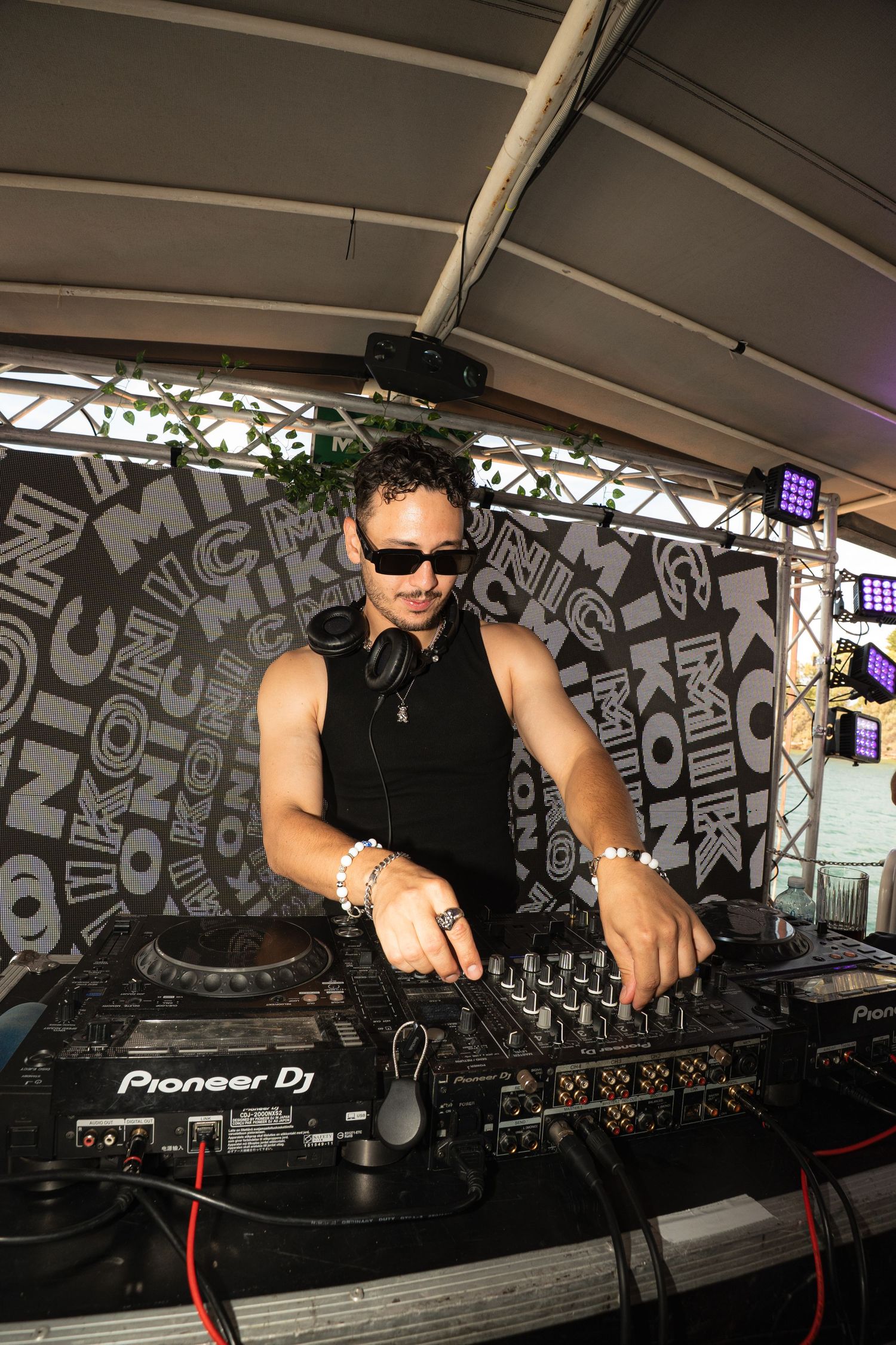 DJ performing on Pioneer equipment at an event with graffiti-style backdrop and stage lighting.