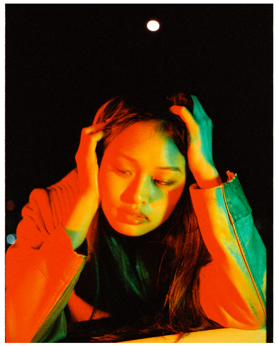 Artistic portrait with dramatic orange and green lighting effects creating a moody atmosphere with deep shadows.
