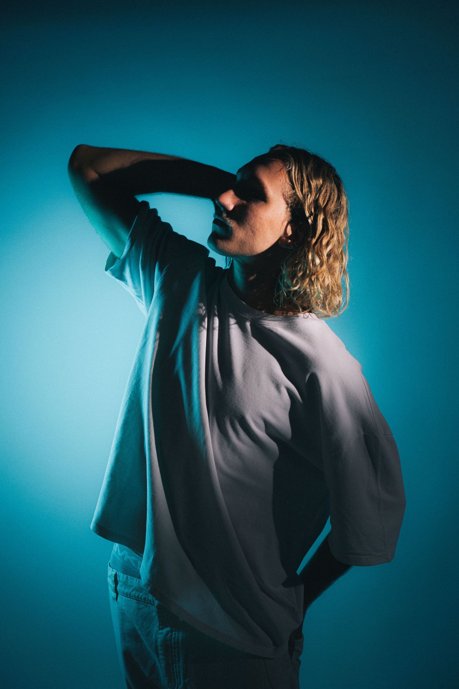 Artistic portrait of a singer performing in moody blue lighting against dark backdrop.