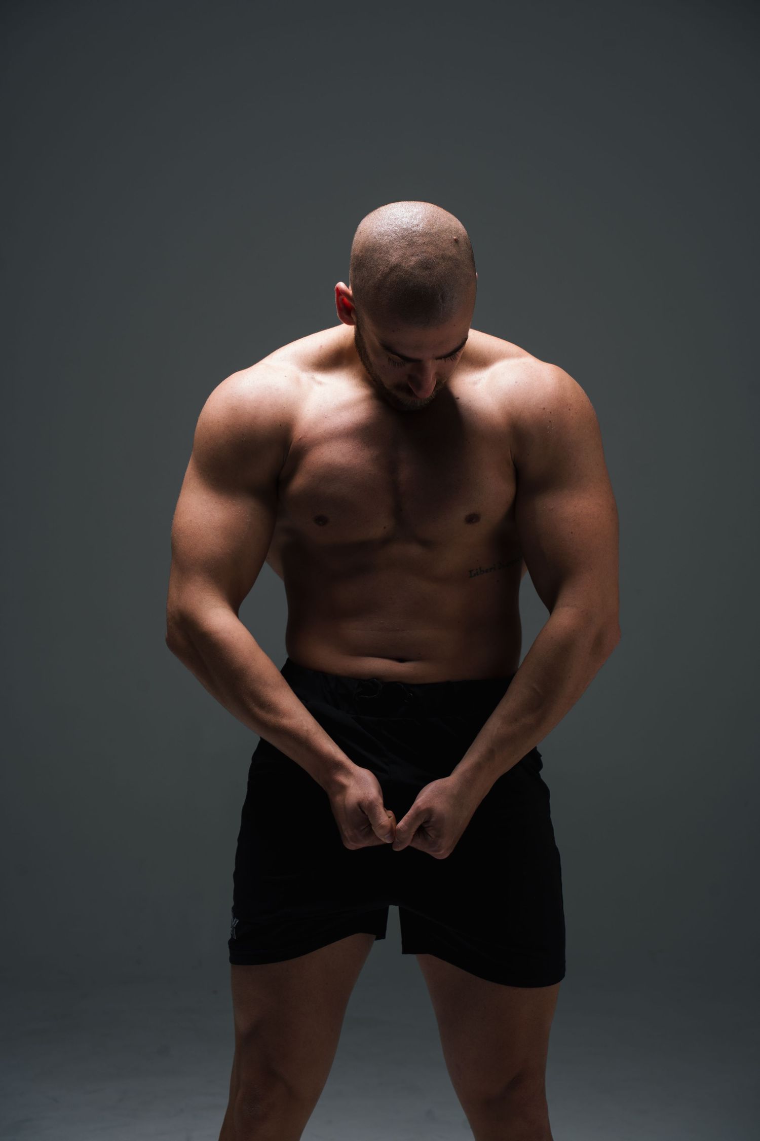 Artistic black and white studio photoshoot showing a muscular torso and body in dynamic poses against dark backdrop.
