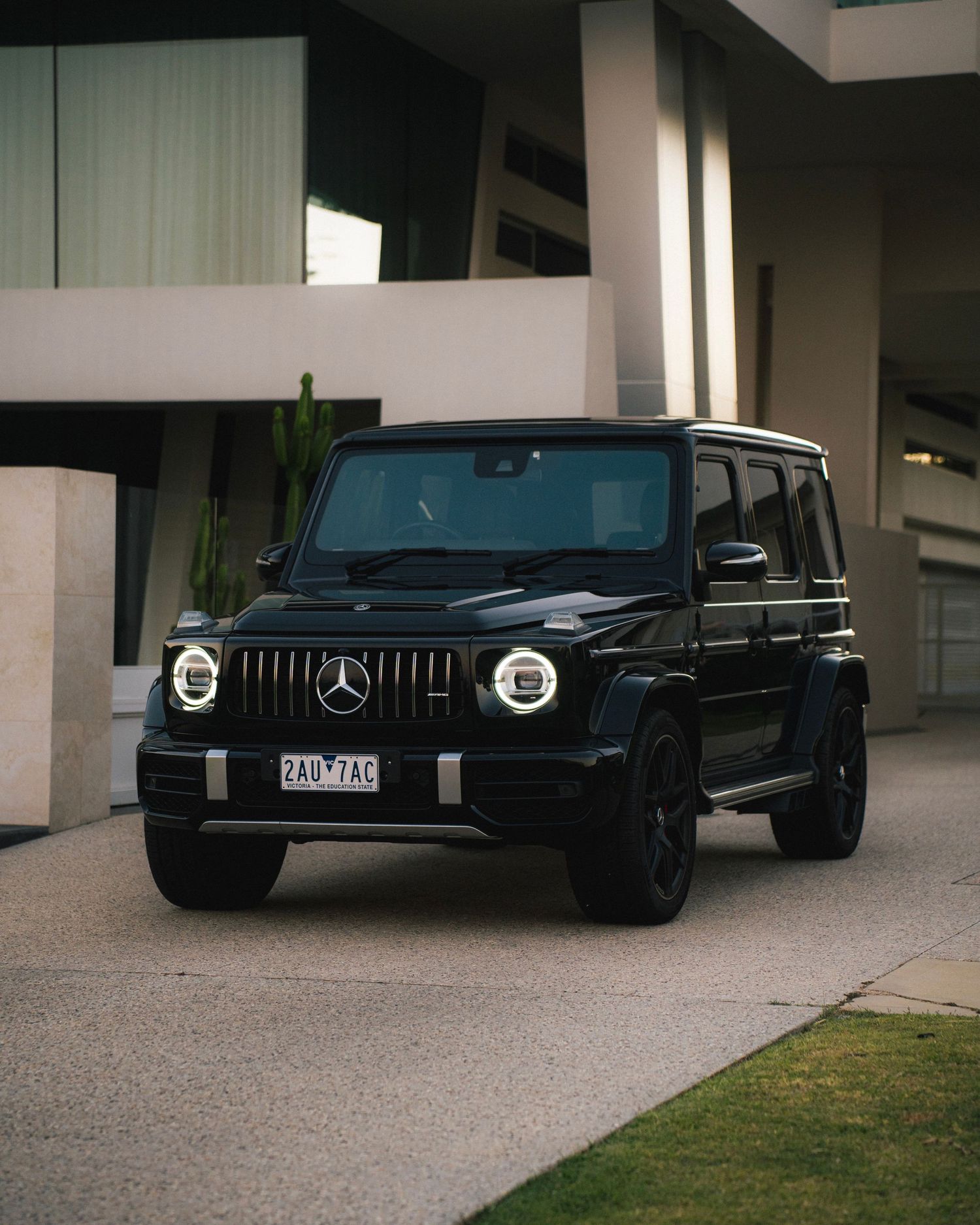Black Mercedes G-Wagon SUV with distinctive circular headlights parked outside a modern building.