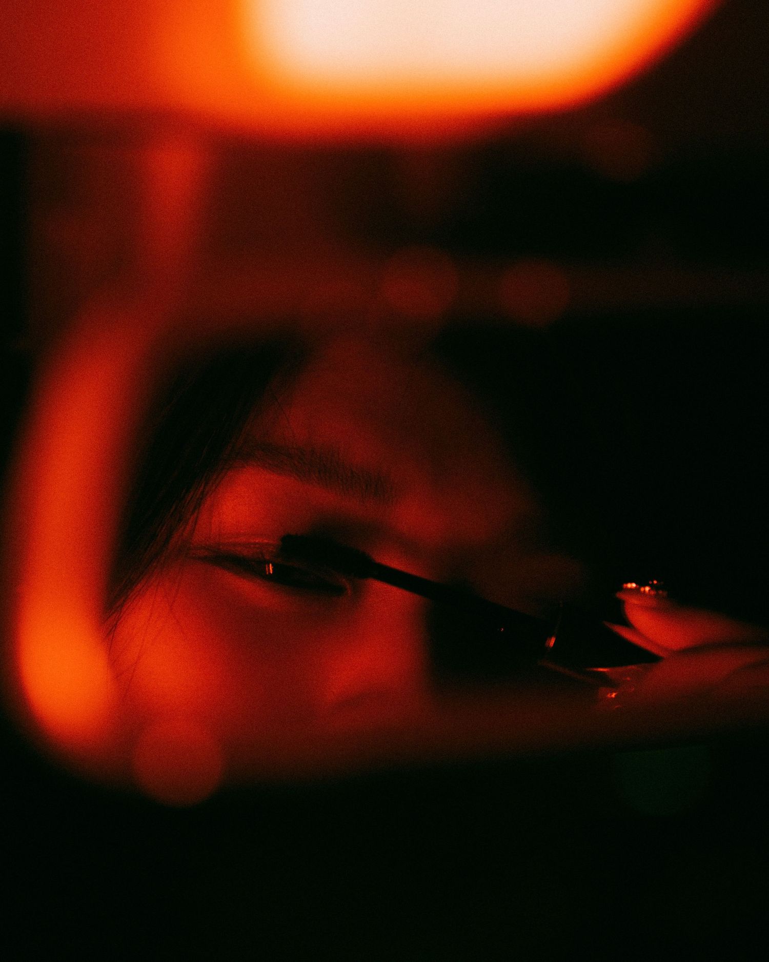 An artistic close-up photograph taken through red lighting shows eyes behind glass or a clear reflective surface.