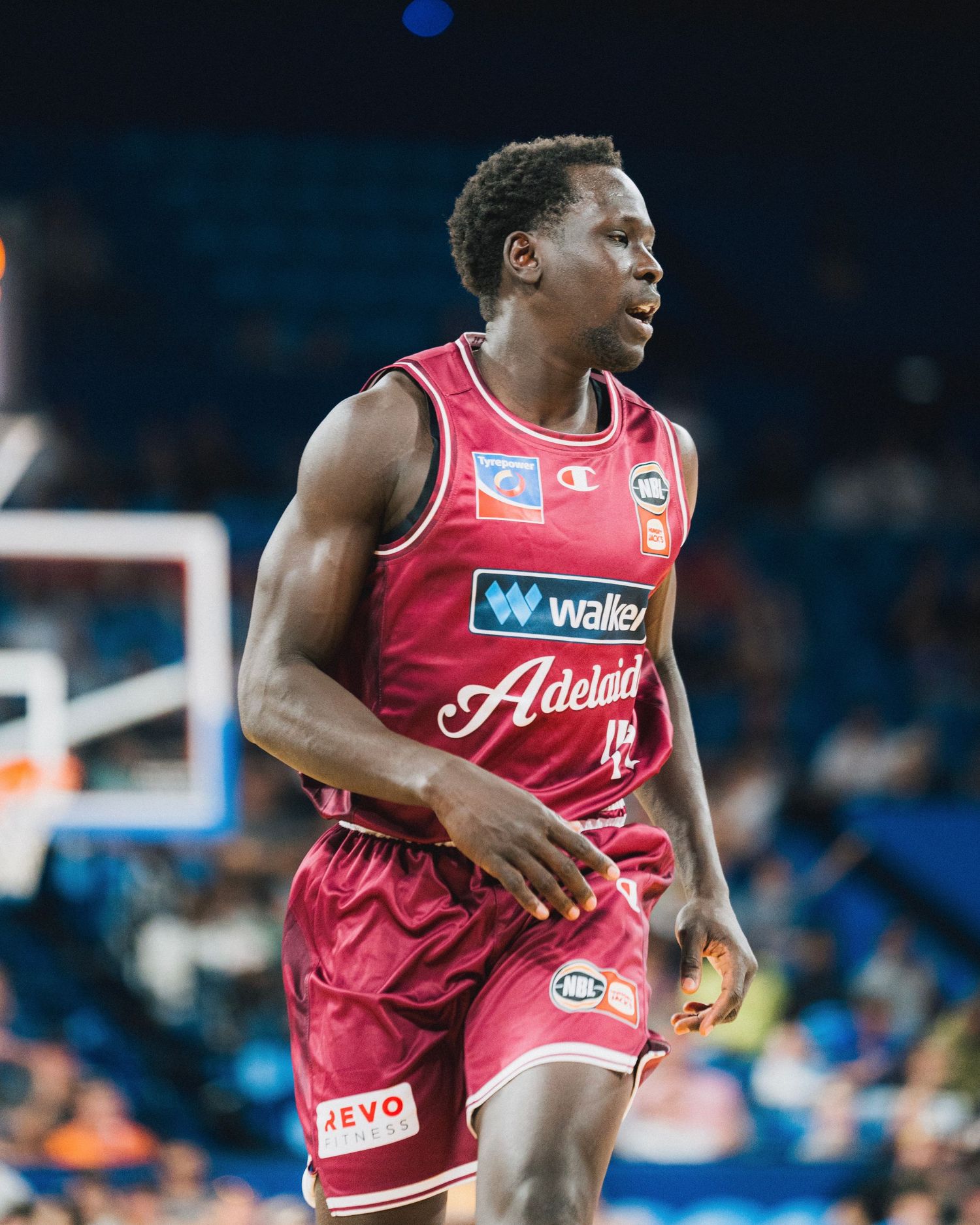 Basketball player in red Adelaide jersey playing on professional court.