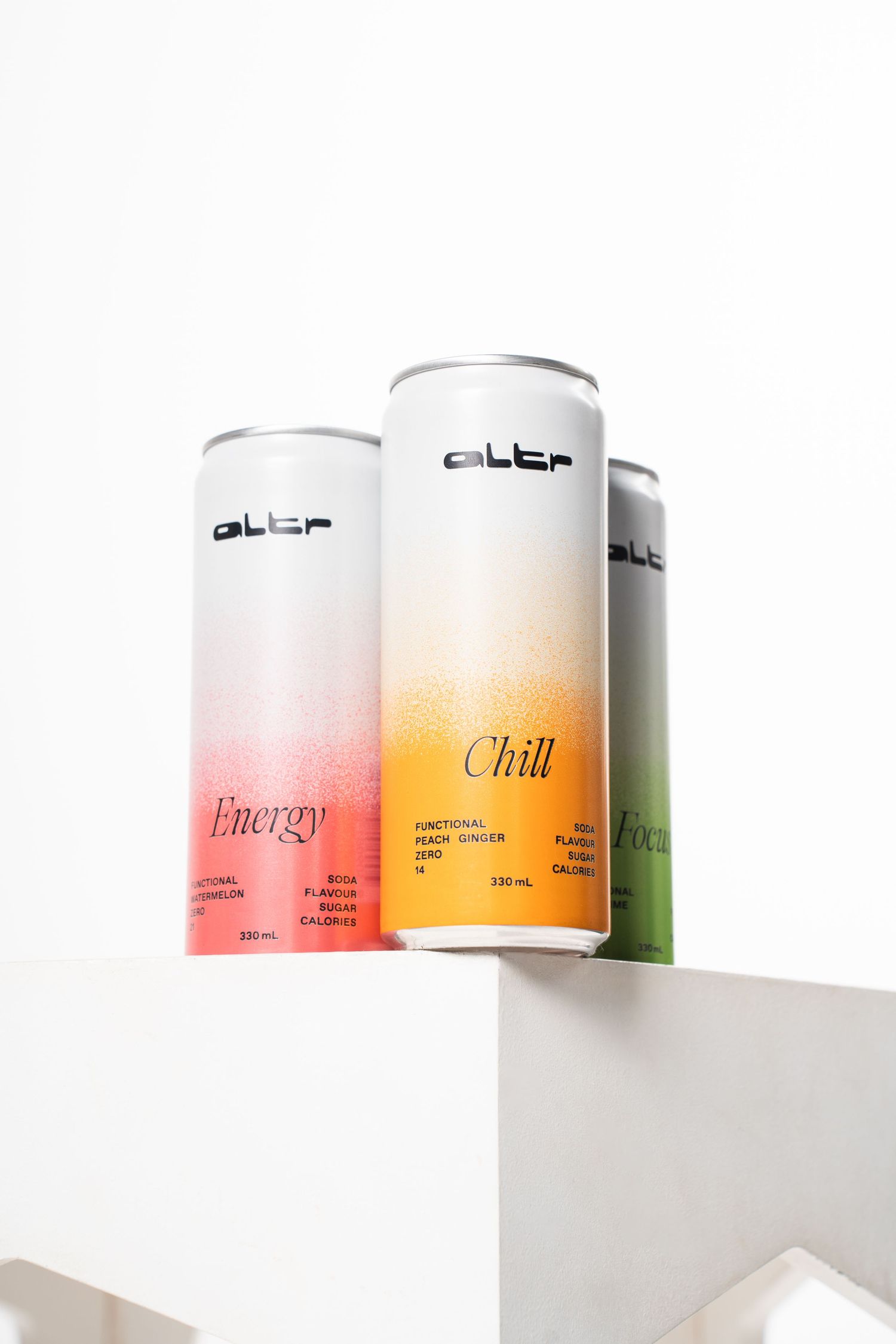 Three minimalist canned beverages labeled Energy and Chill displayed on white geometric surface.