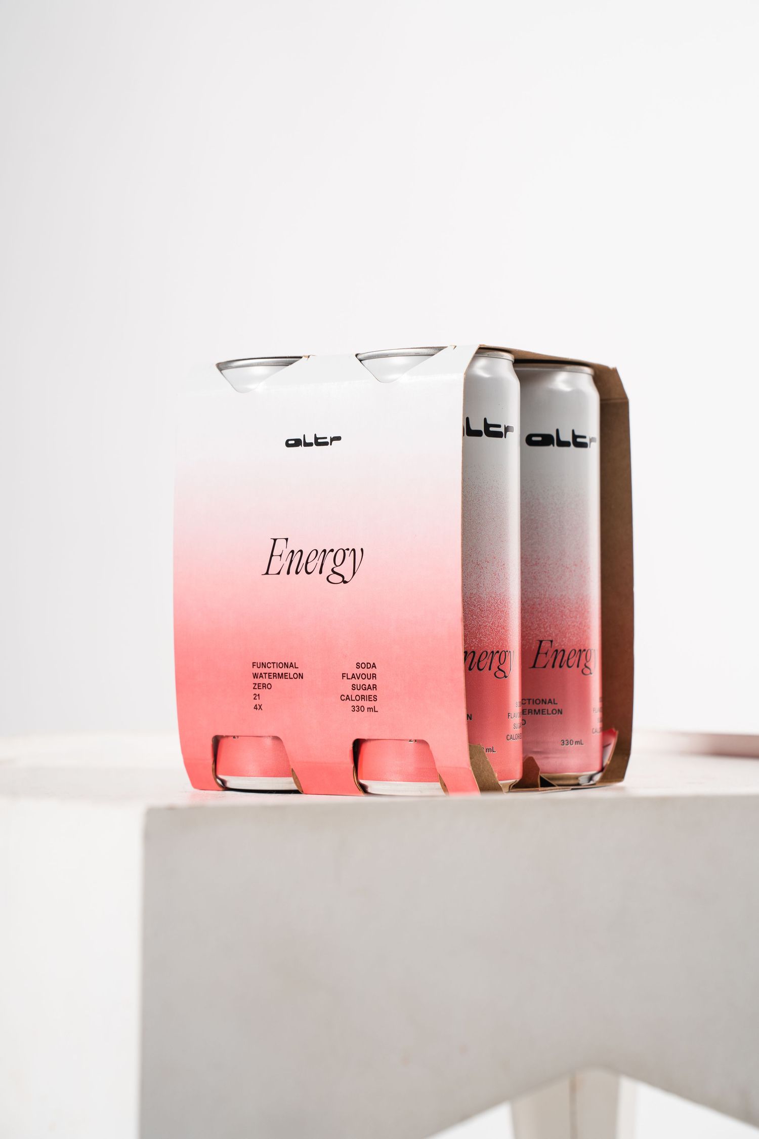 Pink gradient energy drink cans arranged artistically on white pedestal.
