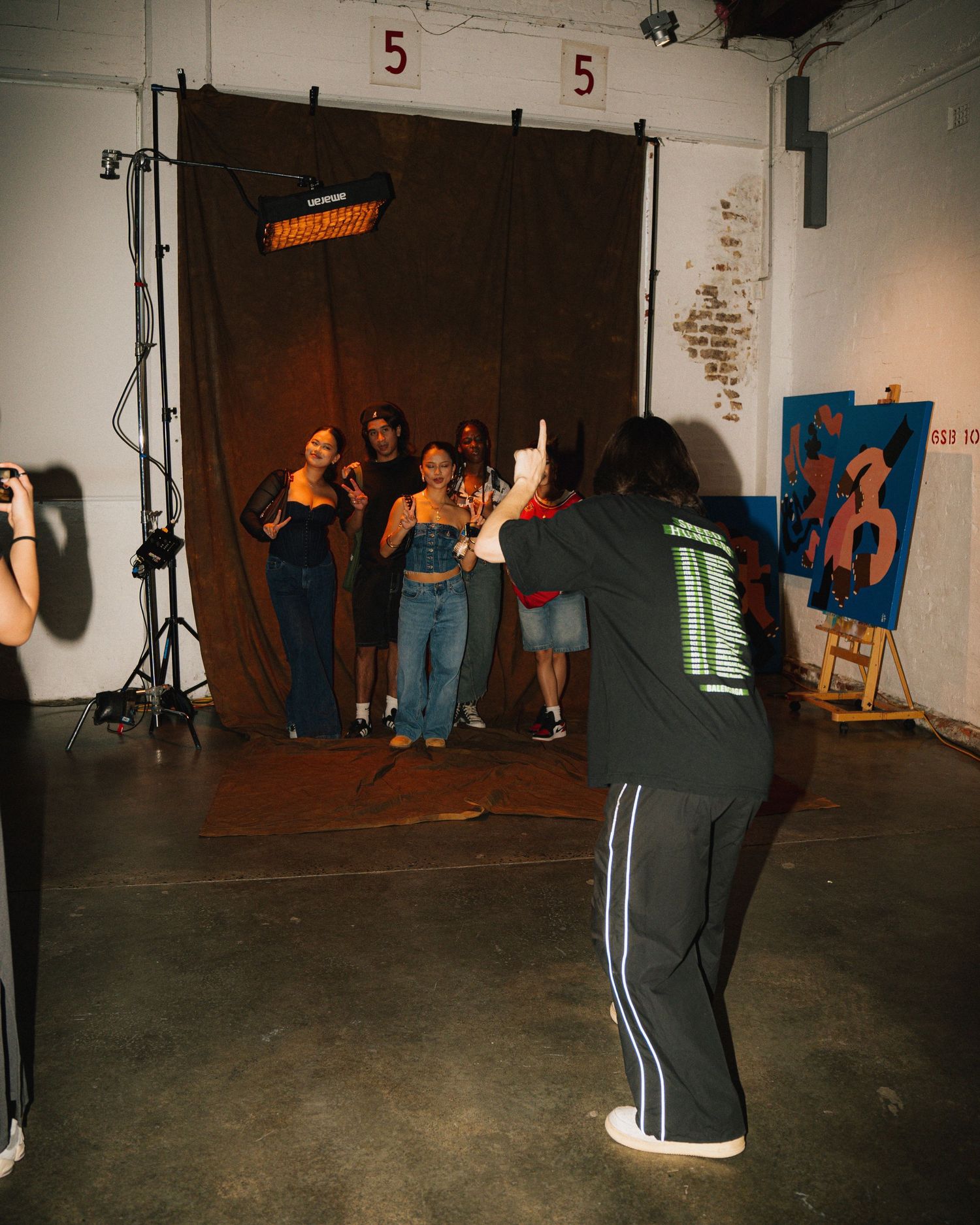 Behind-the-scenes photo shoot with photographer directing subjects in studio space.
