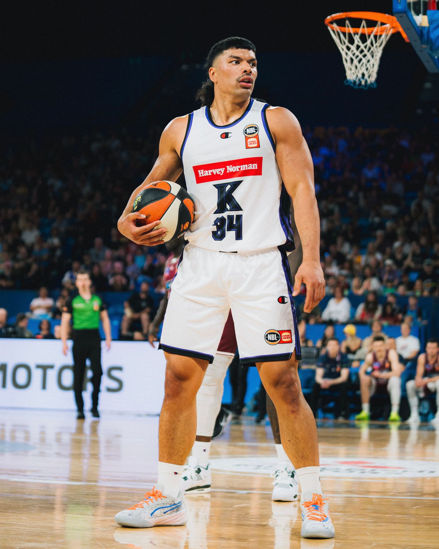 Basketball player in white uniform holds ball on professional court during game.