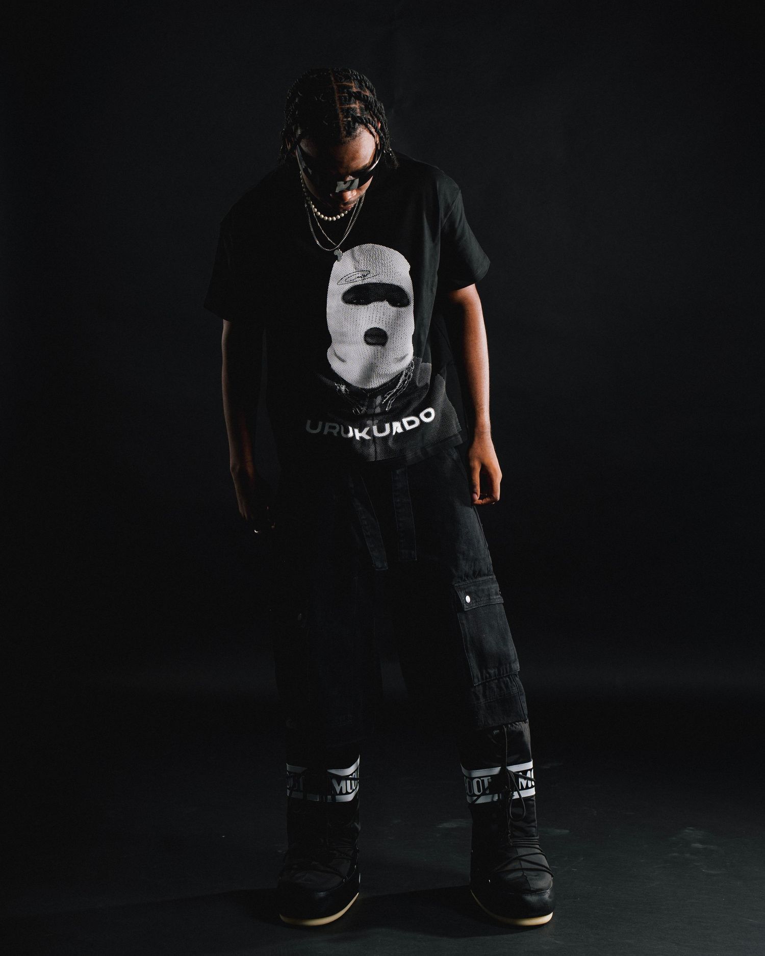 Streetwear model poses in dark setting wearing graphic t-shirt and baggy pants.