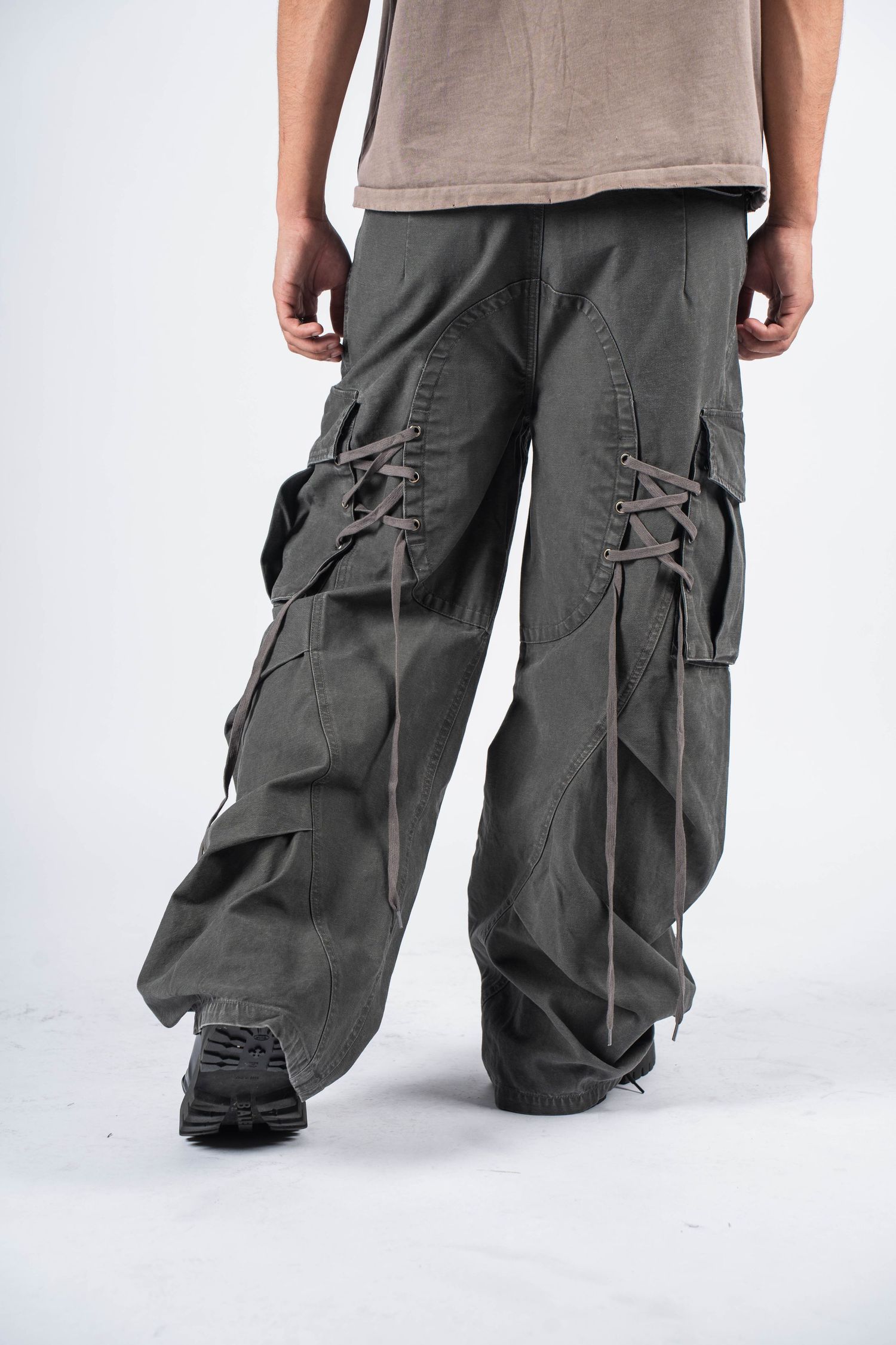 Wide-leg grey cargo pants with multiple pockets and straps shown from behind.