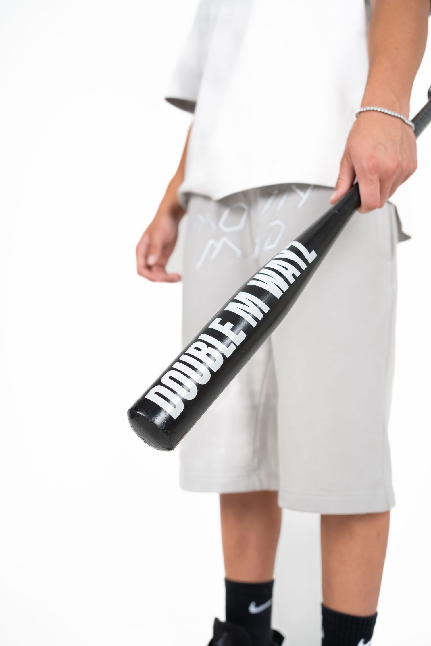 A close-up shot of someone holding a black baseball bat against a white background.