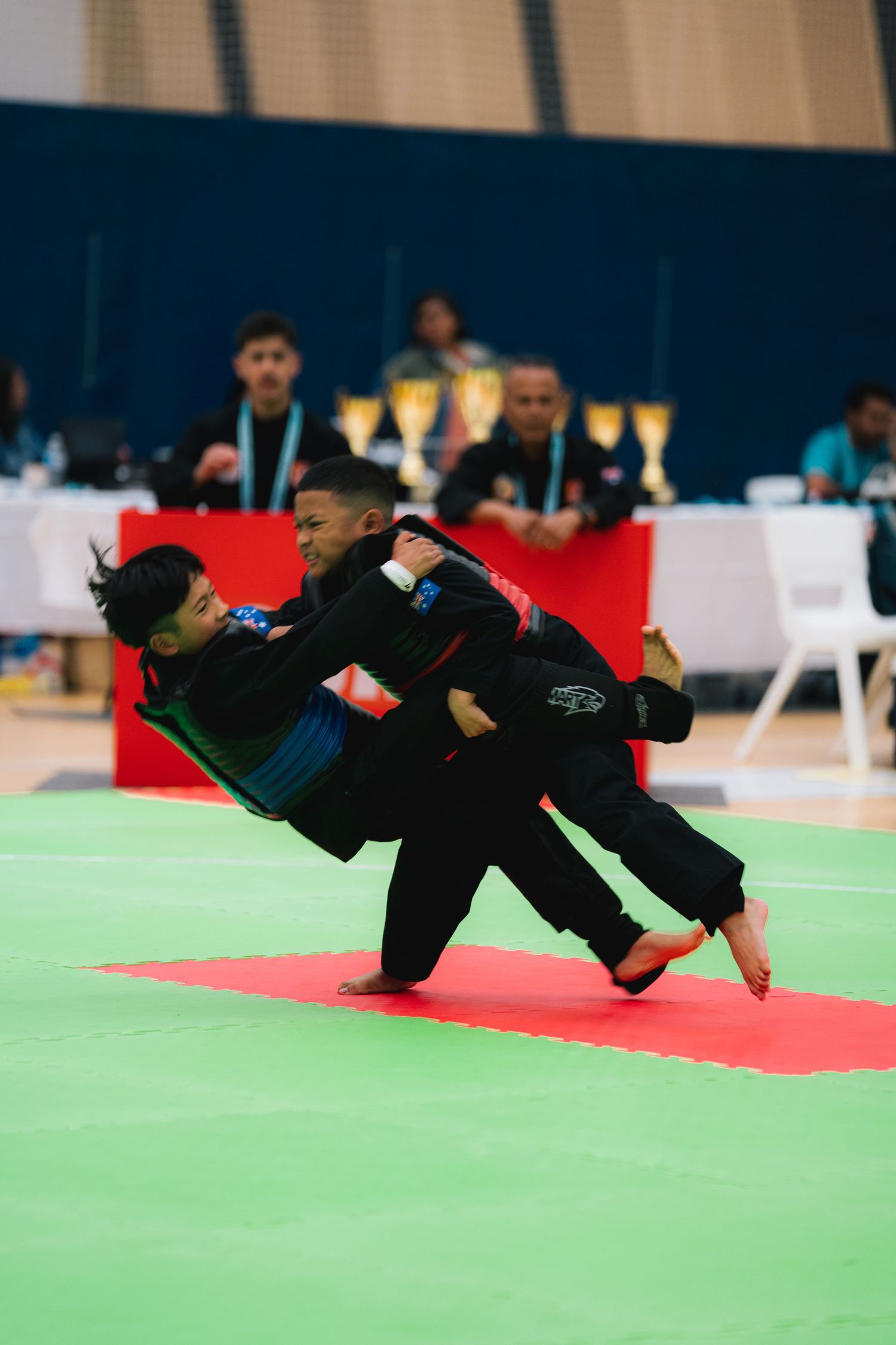 Martial arts competitors demonstrate grappling techniques during a tournament match.