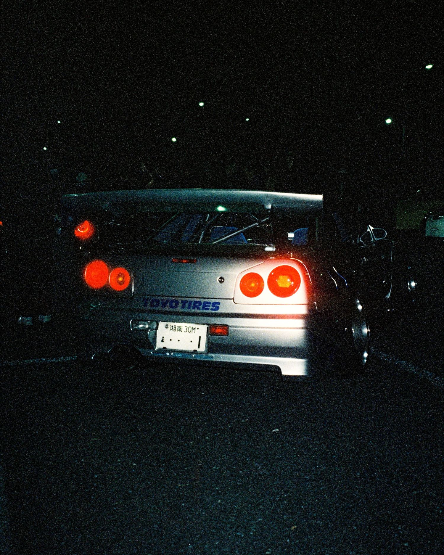 Illuminated taillights of a Nissan Skyline GTR R34 captured at night.