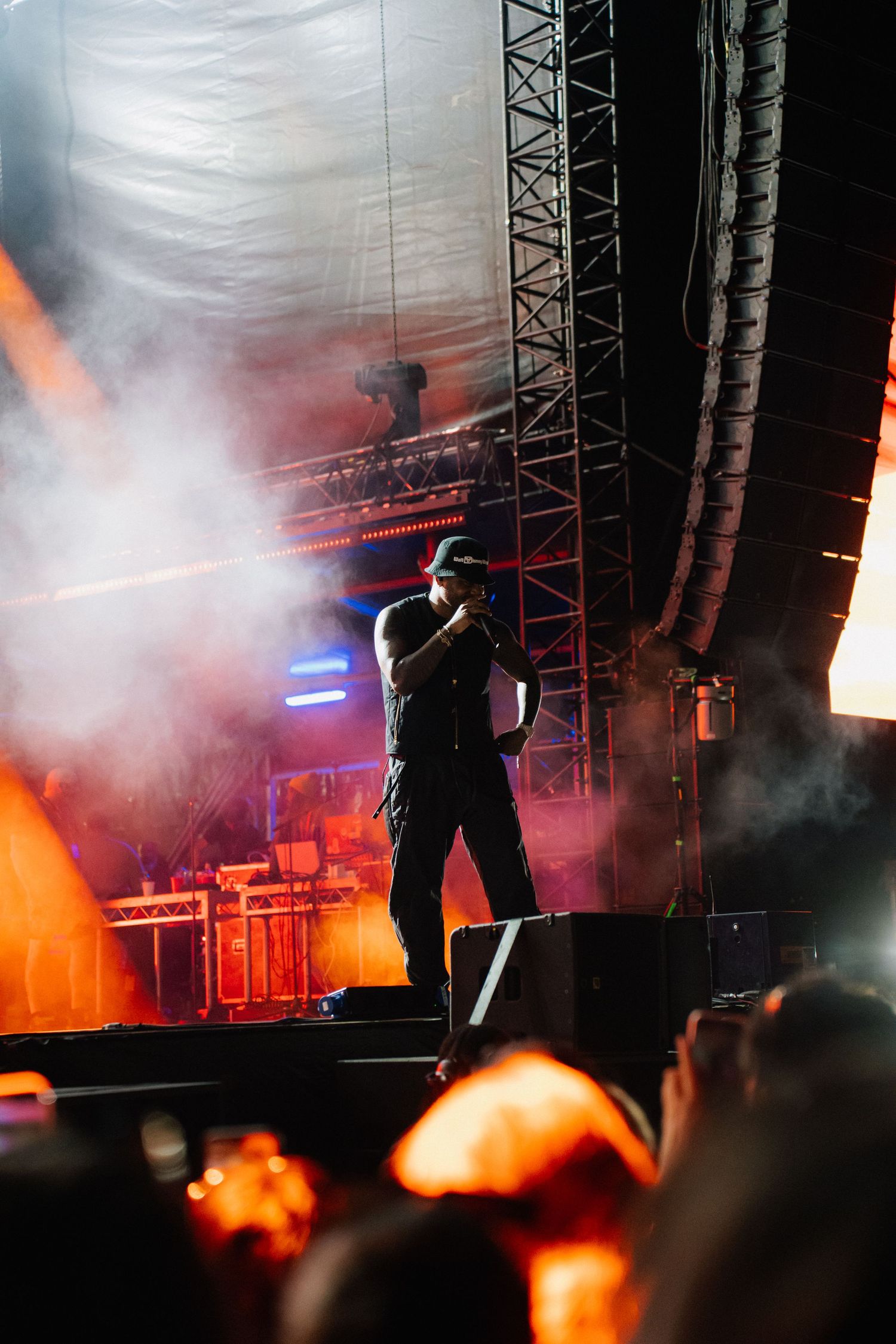 Concert performer silhouetted on stage amid dramatic orange lighting and smoke effects during nighttime performance.