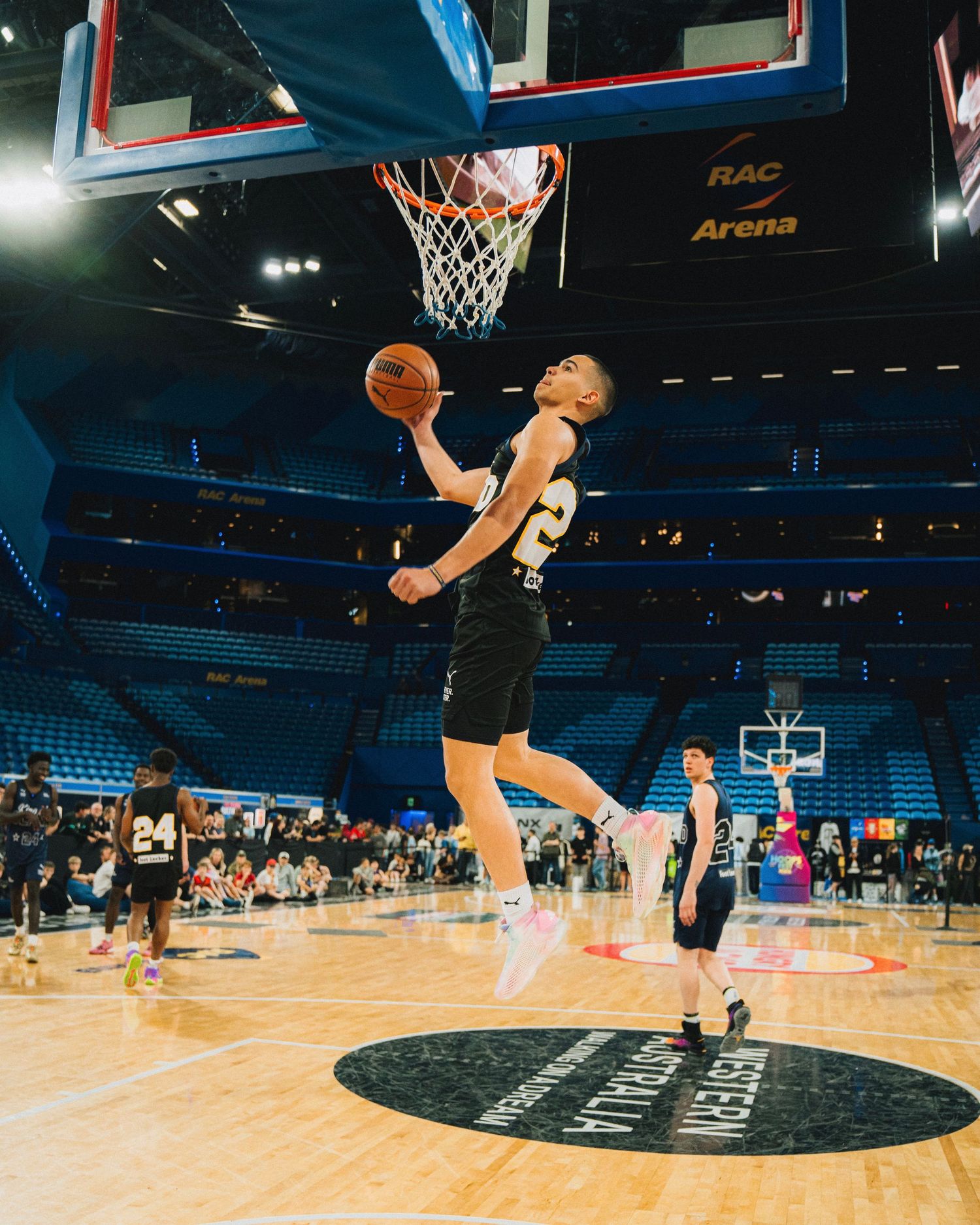 Player performs a dramatic slam dunk attempt in an empty arena with blue seats.
