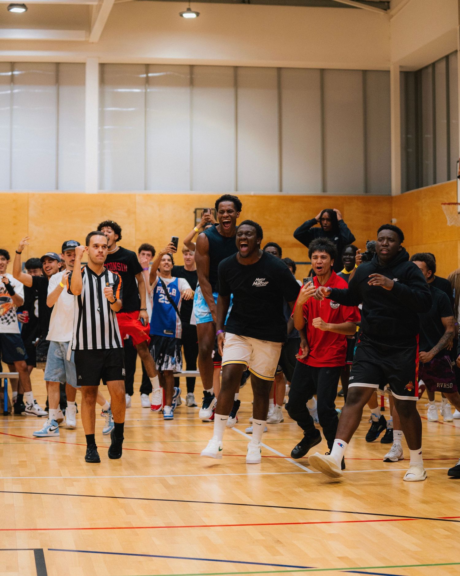 Enthusiastic crowd jumping and celebrating in a gymnasium during an indoor event.