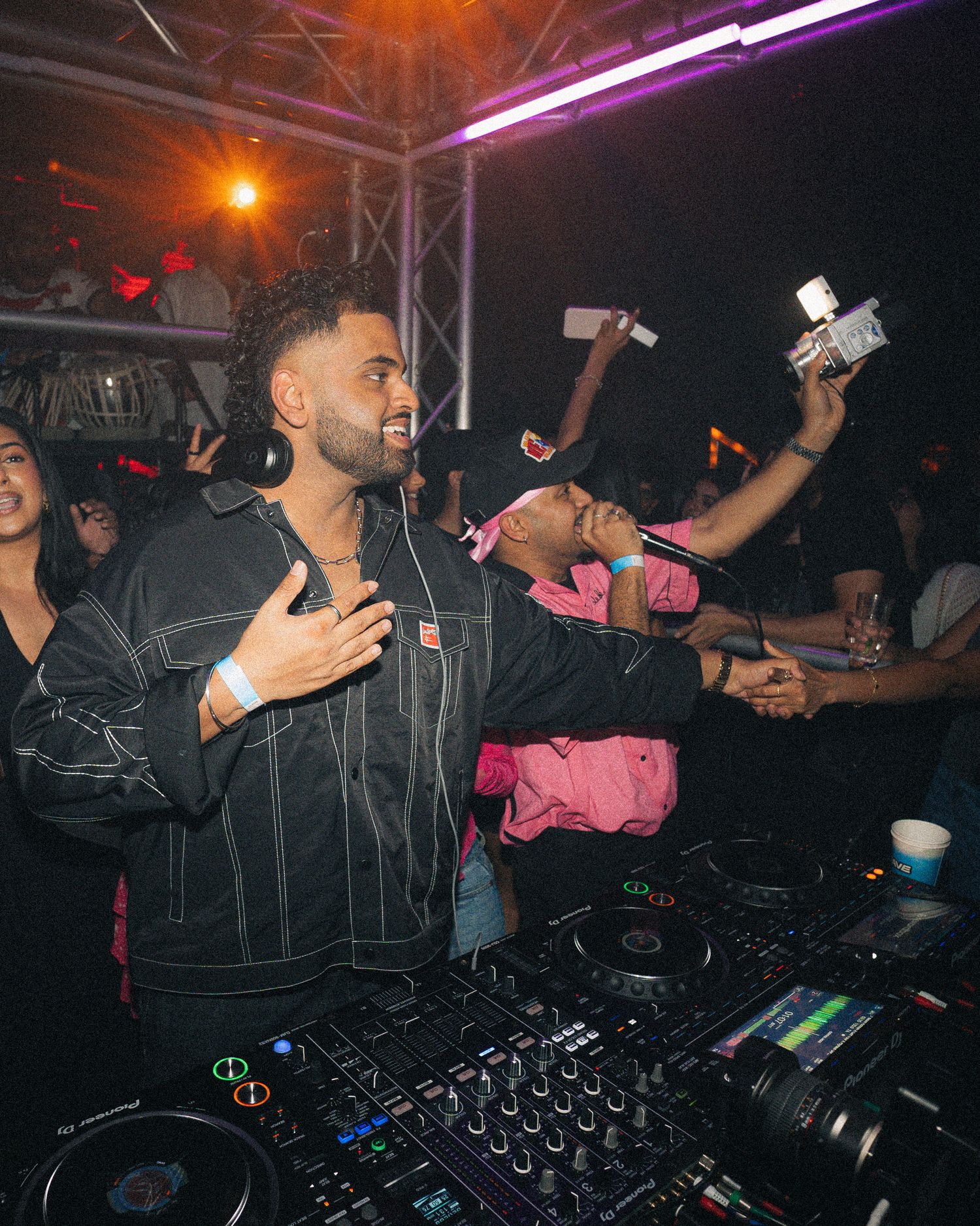 DJ performing at nightclub with blue and orange lighting effects.