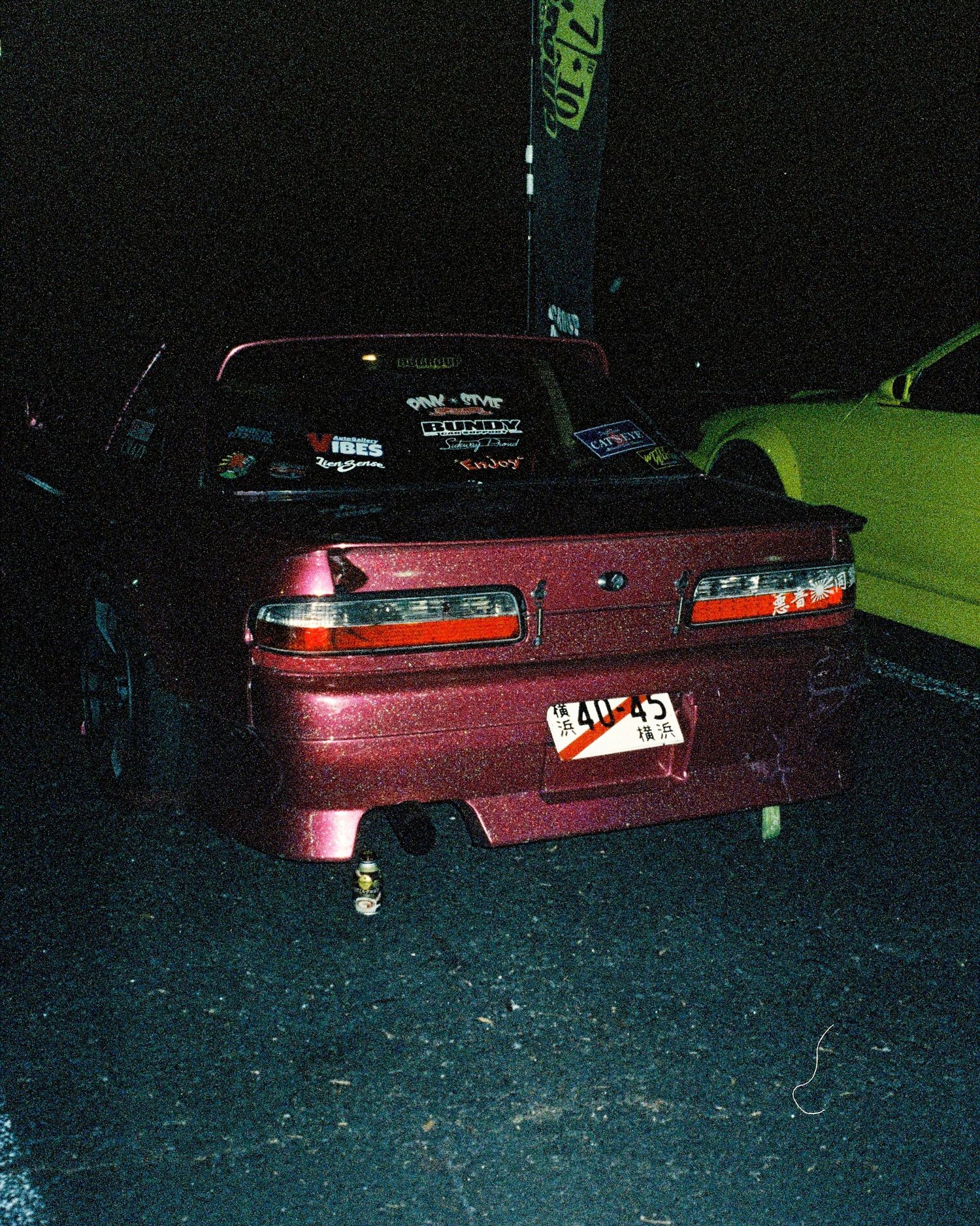 Modified maroon Nissan Silvia S13 with aftermarket body kit at night car meet.